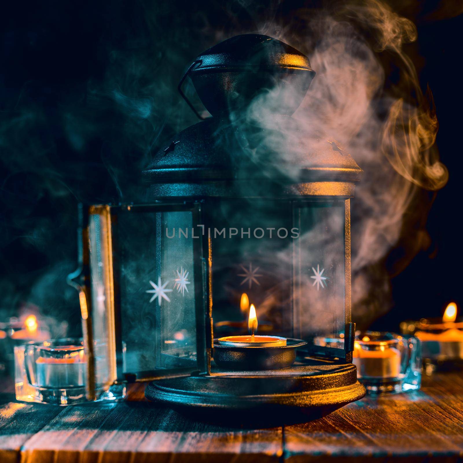 Halloween concept, spooky decorations with lighting up candle and candle holder with green tone smoke around on a dark wooden table, close up.