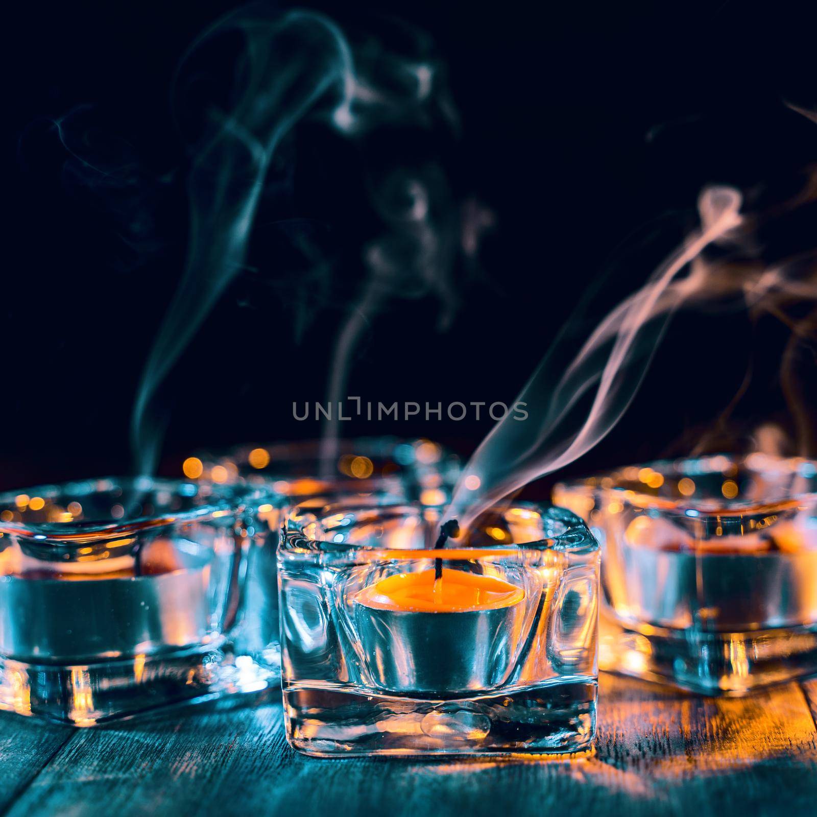 Halloween concept, spooky decorations with lighting up candle and candle holder with green tone smoke around on a dark wooden table, close up.