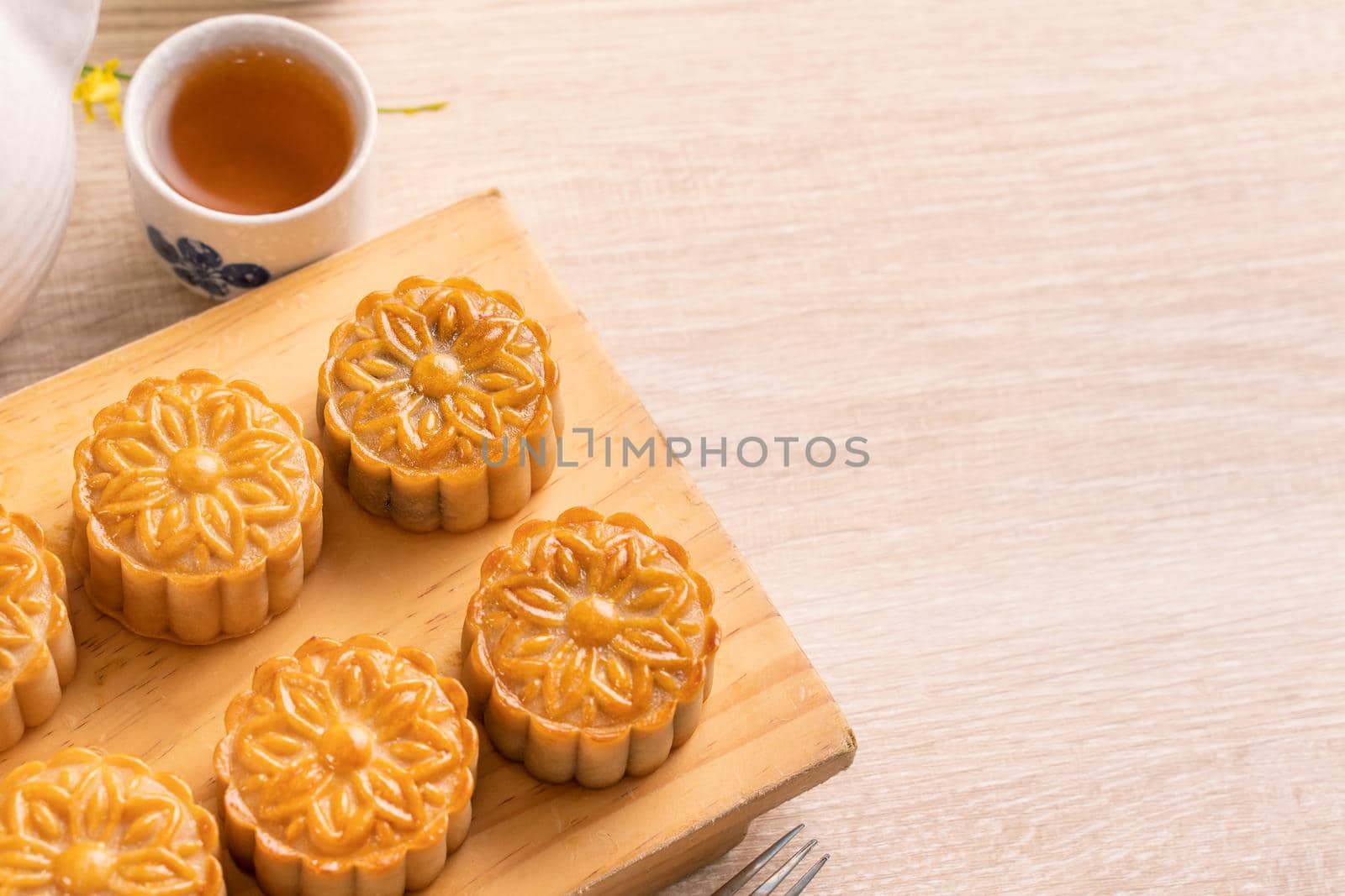 Moon cakes with tea on bright wooden table and serving try, holiday concept of Mid-Autumn festival traditional food layout design, close up, copy space.