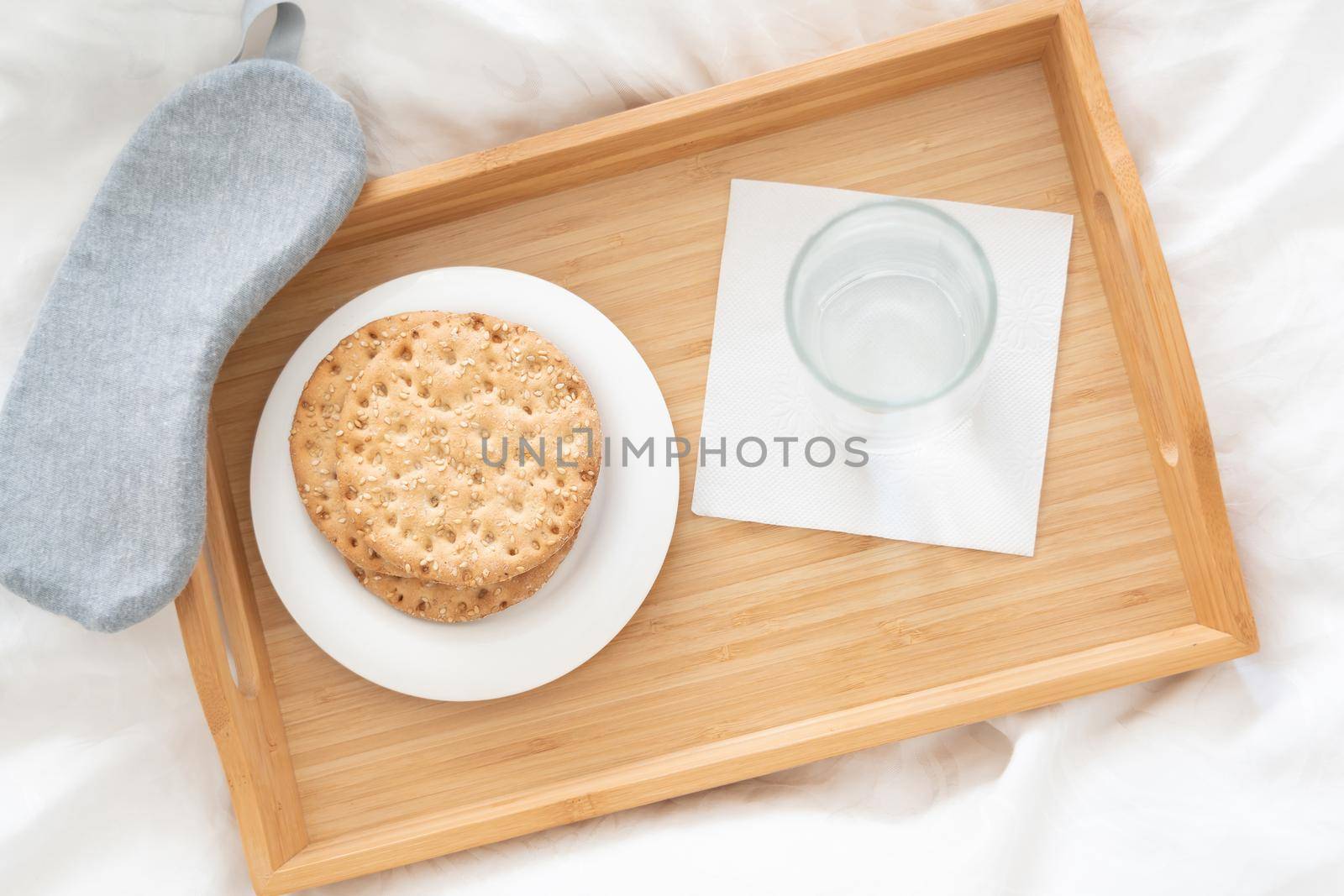 Tray with water and crackers dibreakfast on a bed by Mariakray