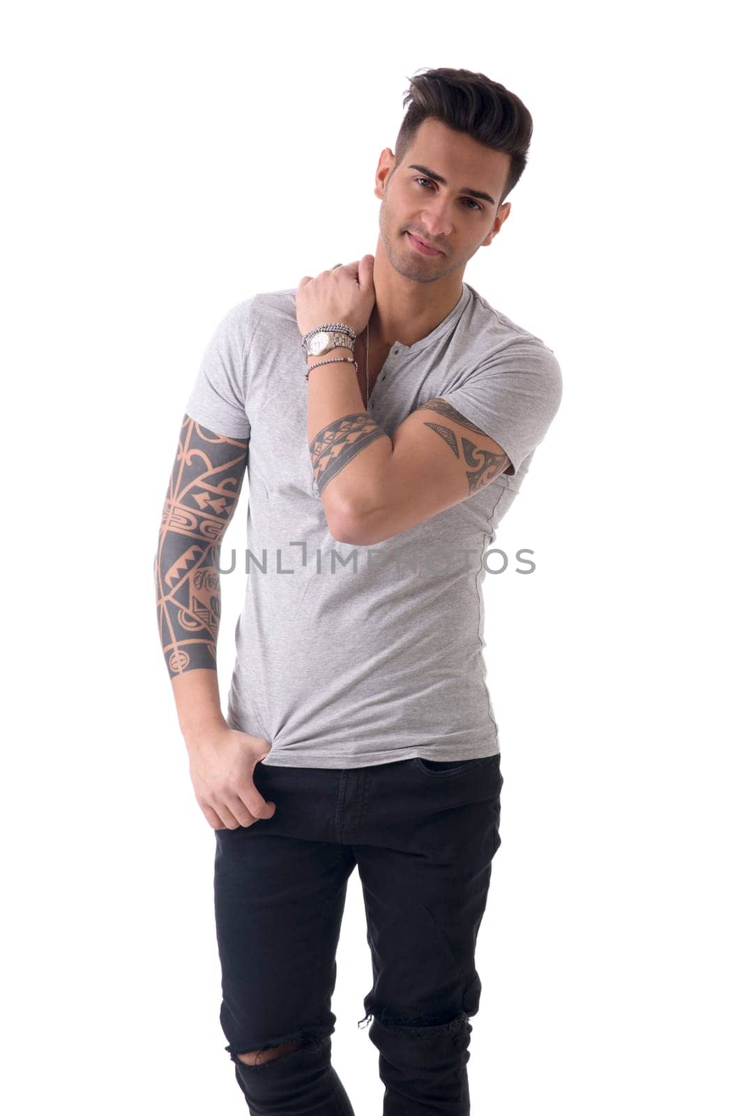 Handsome tattooed young man wearing grey t-shirt, standing isolated against white background in studio shot