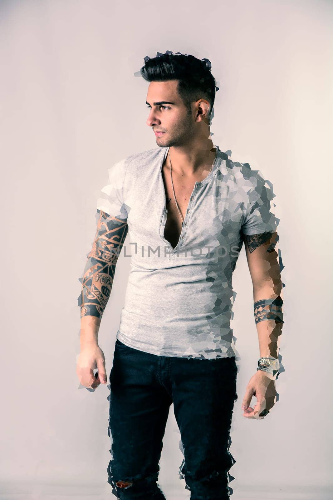 Handsome tattooed young man wearing grey t-shirt, standing isolated against white background in digitally processed shot