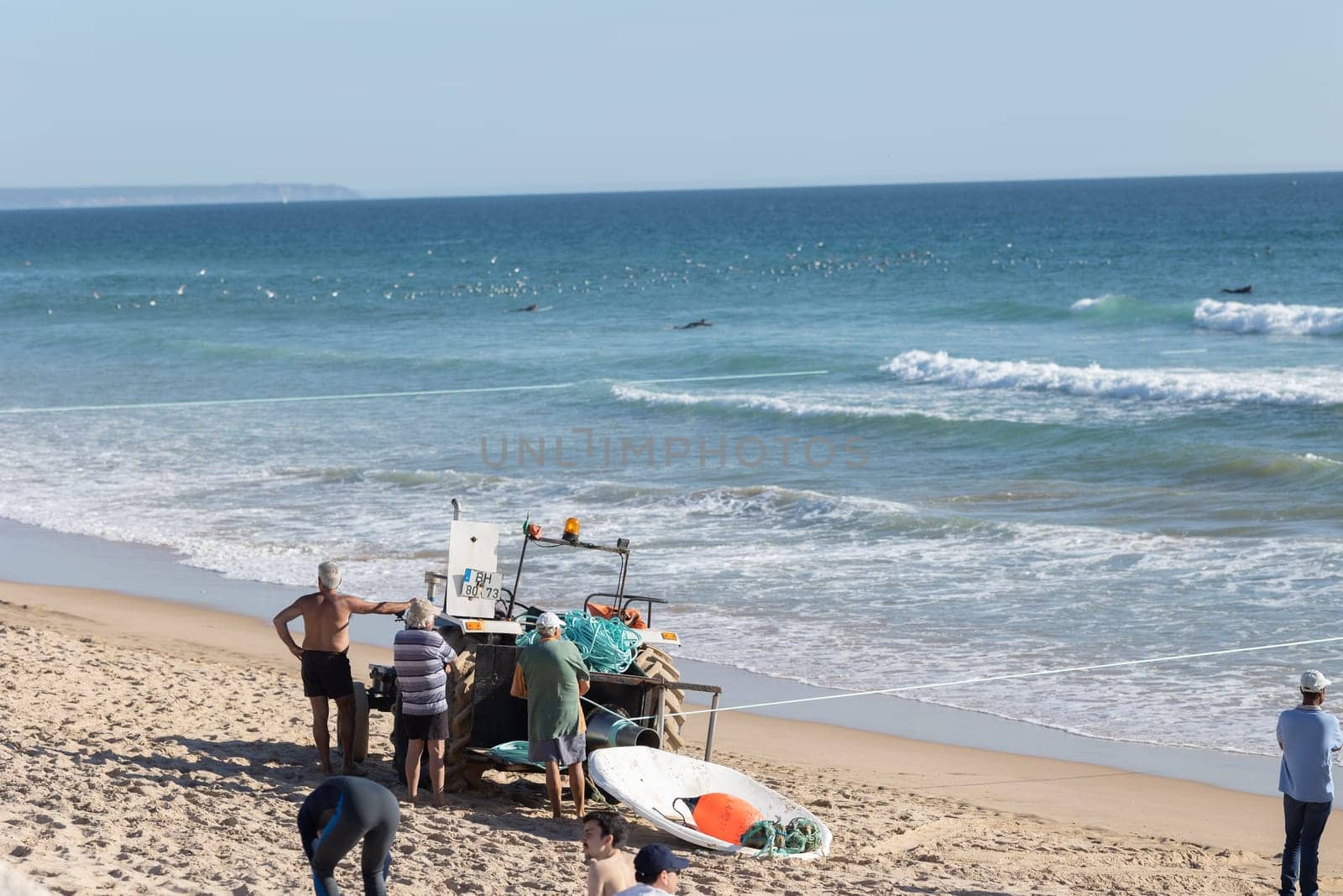 24 April 2023 Lisbon, Portugal: fishermen standing by tractor and catching fish on the seashore. Mid shot