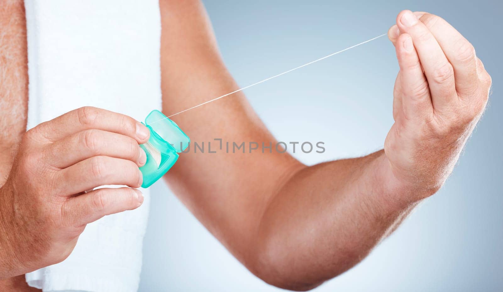 Hands, dental and floss product in studio isolated on a blue background for oral hygiene. Health, wellness and senior man model holding container with thread for flossing, cleaning and teeth care