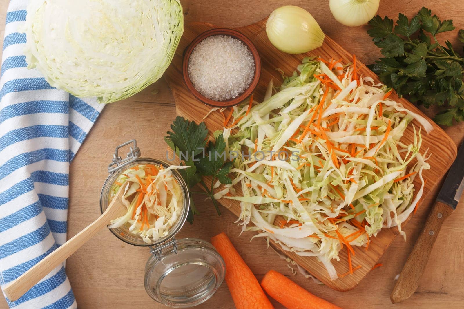 Sliced cabbage on a wooden board with carrots, onions and herbs. Preparing to cook coleslaw