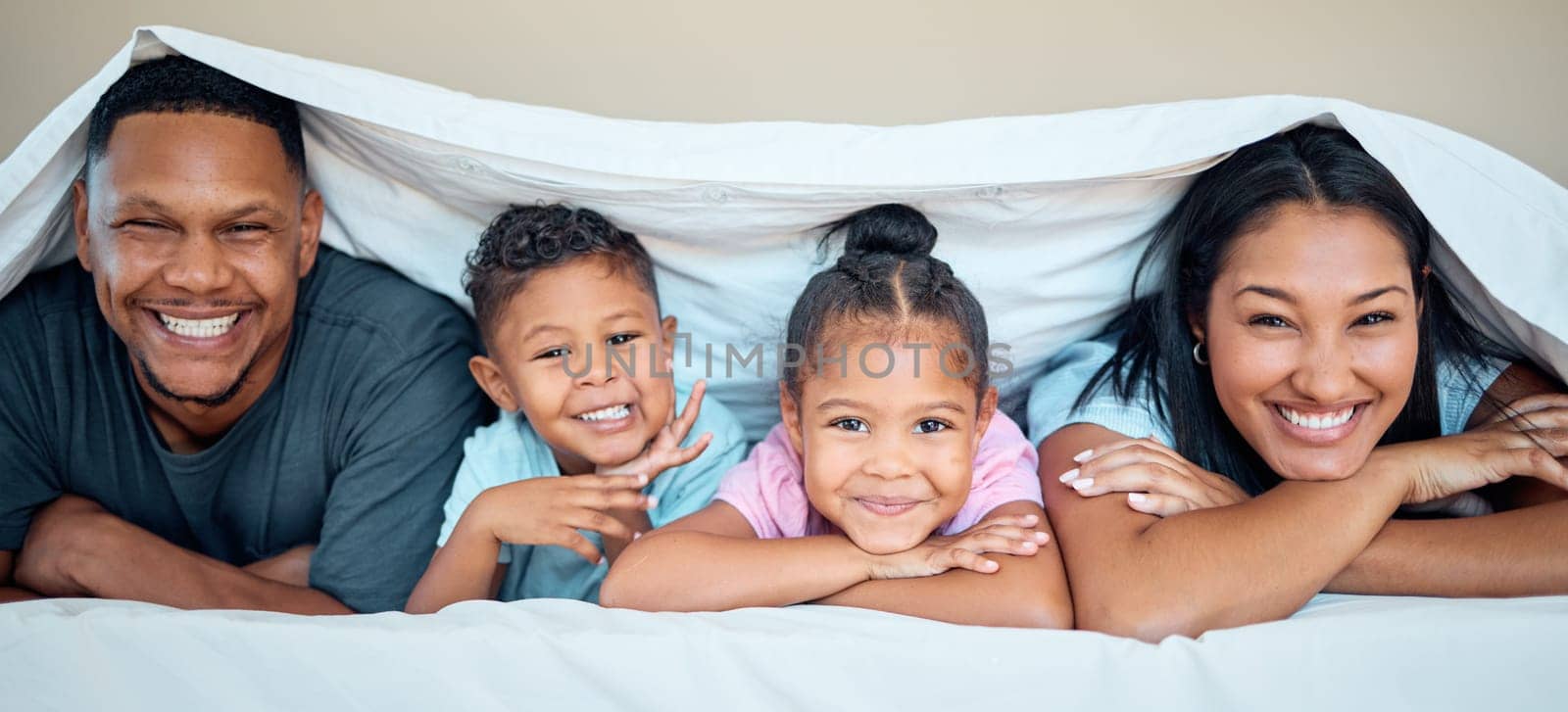 Love, blanket and happy family in bed together for quality time, care and support with smile. Relax, parents and children portrait for relationship bonding happiness lifestyle in family home bedroom.