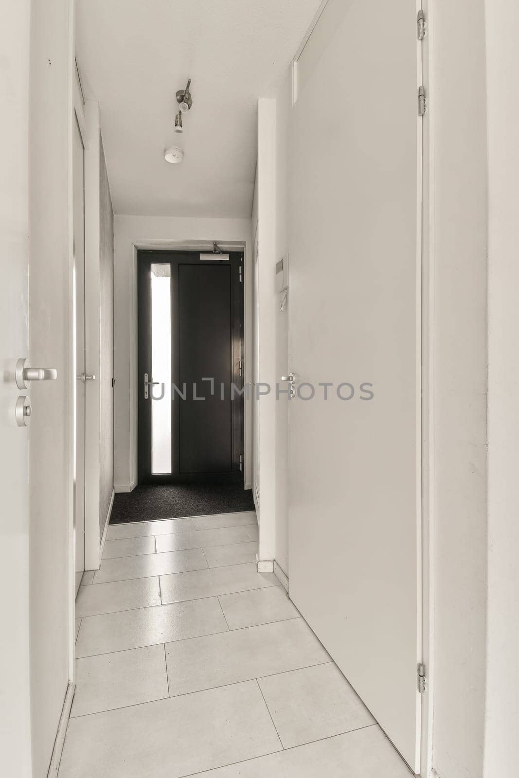 a long hallway with white walls and black door handle on the left side of the room, there is an open door