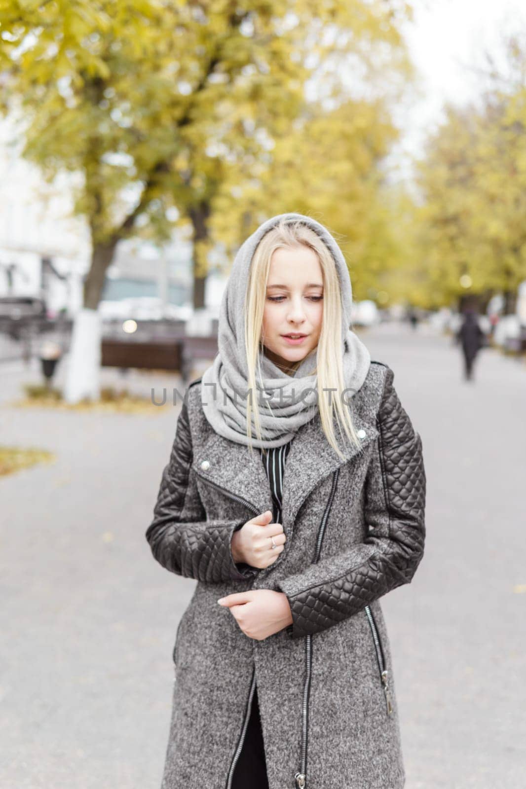 A young blonde walks through the autumn city in a gray coat. The concept of urban style and lifestyle. by Annu1tochka