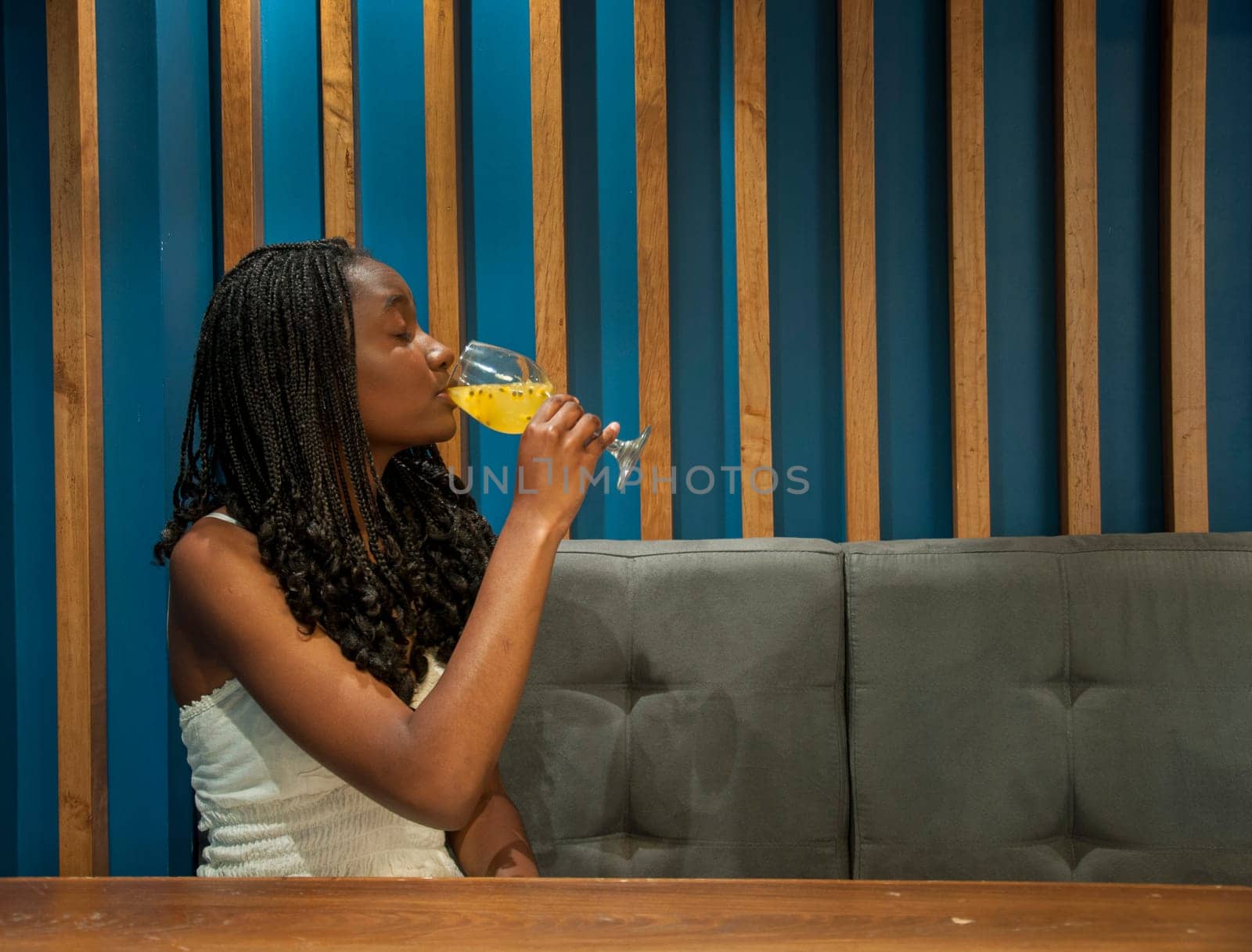 copyspace afro girl drinking a refreshing passion fruit drink in profile to the camera. High quality photo
