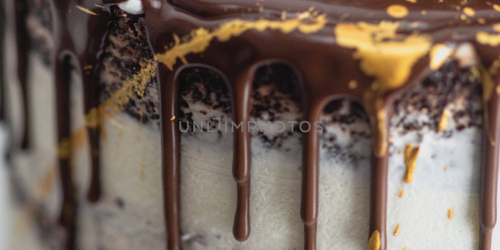 studio shot of chocolate frosted dripped icing cup cake with sweet fruit topping and golden brush strokes