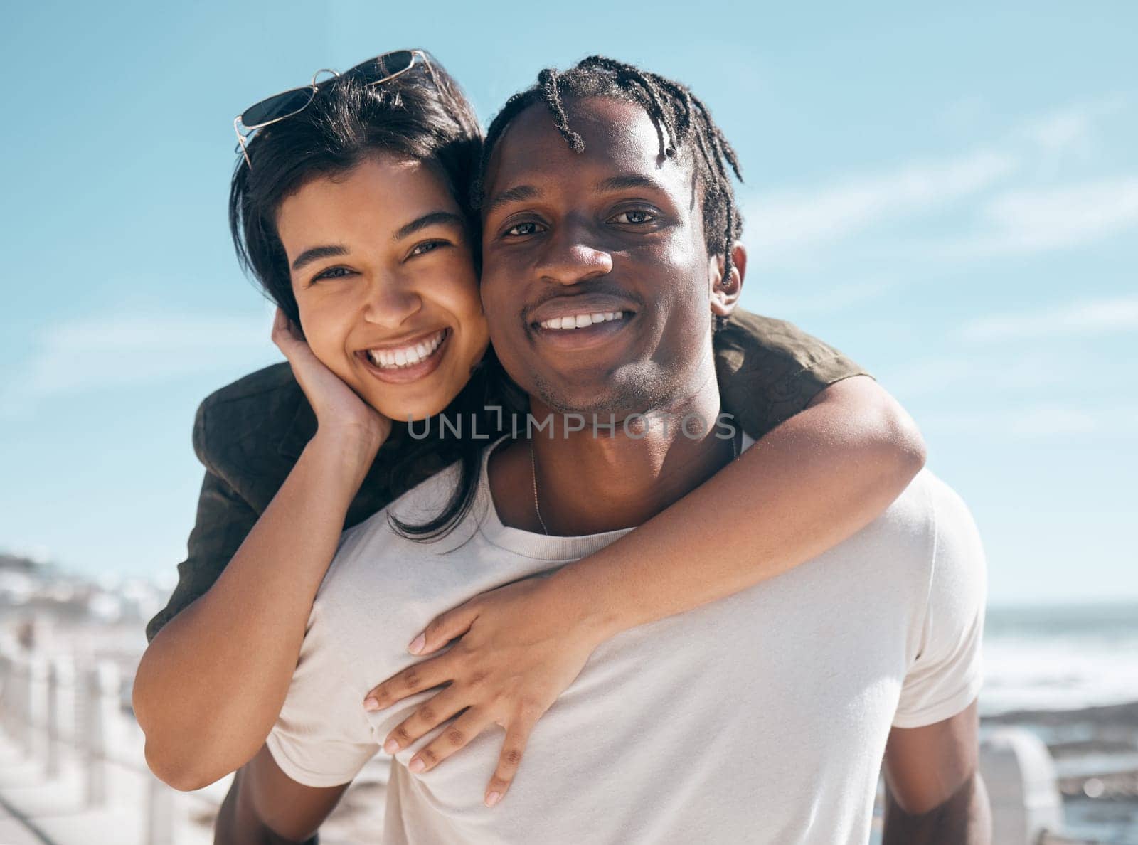 Happy couple, portrait and piggyback by beach in relax romance holiday, love vacation date or summer travel location. Smile, bonding and man carrying black woman in fun game, freedom trust or support.