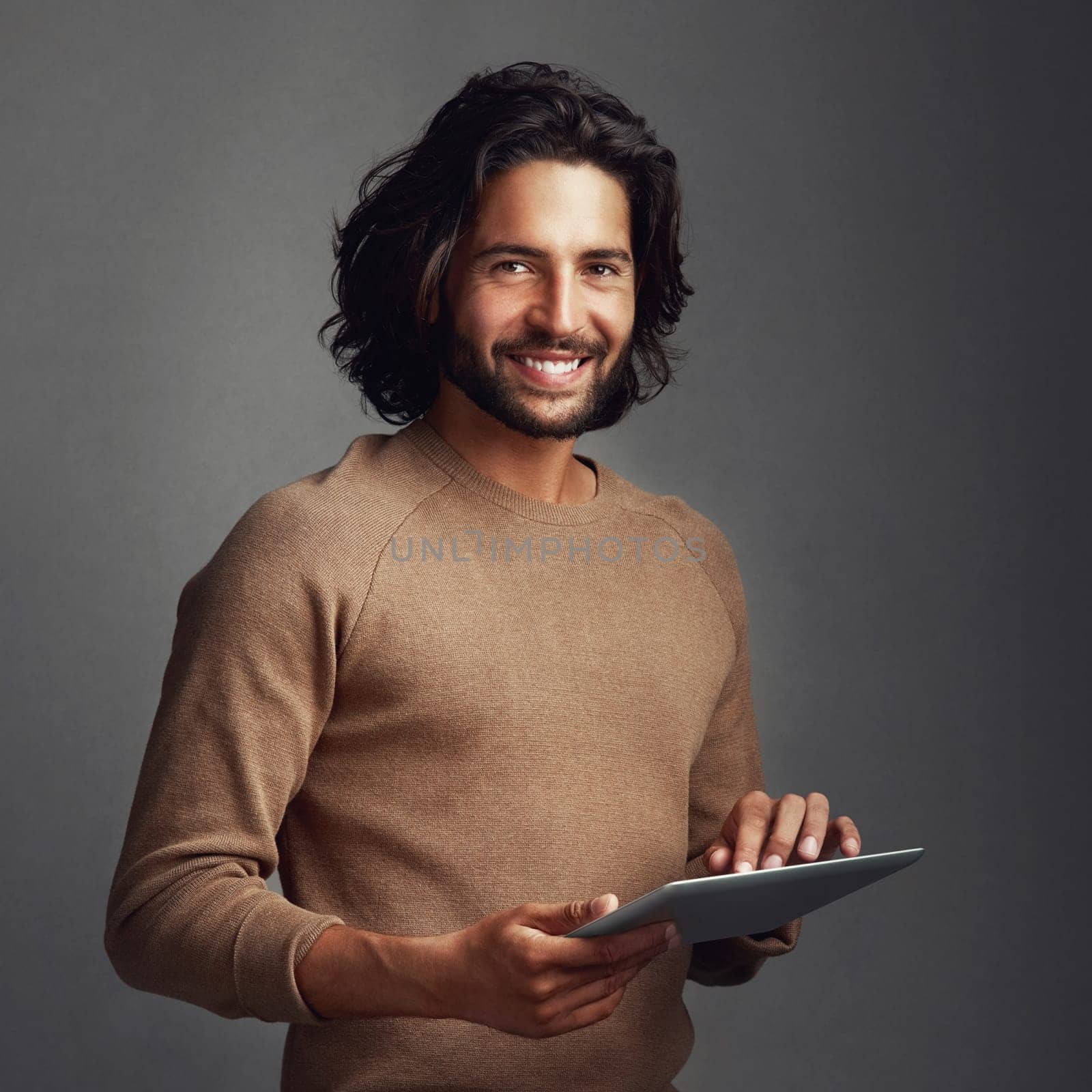 I keep my lifestyle digitized. Studio shot of a handsome young man using a digital tablet against a gray background