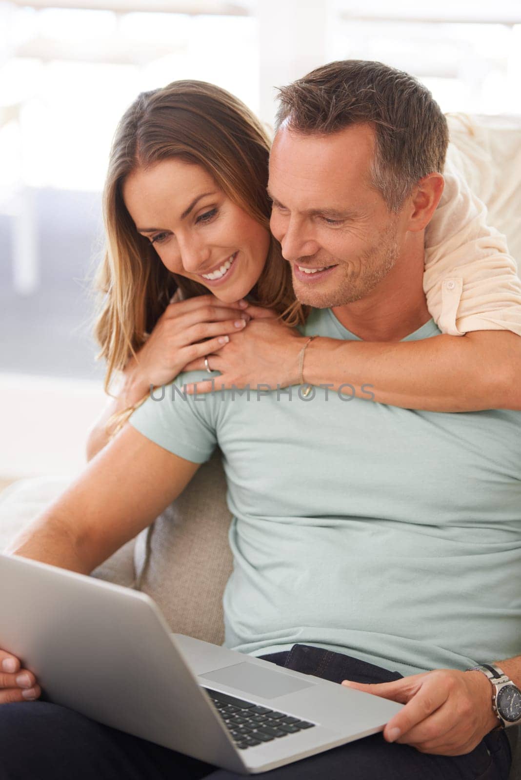 Computer, sofa and happy couple with home internet for online planning, website review or check application together. Hug, love and affection of mature woman, partner or people on laptop technology by YuriArcurs