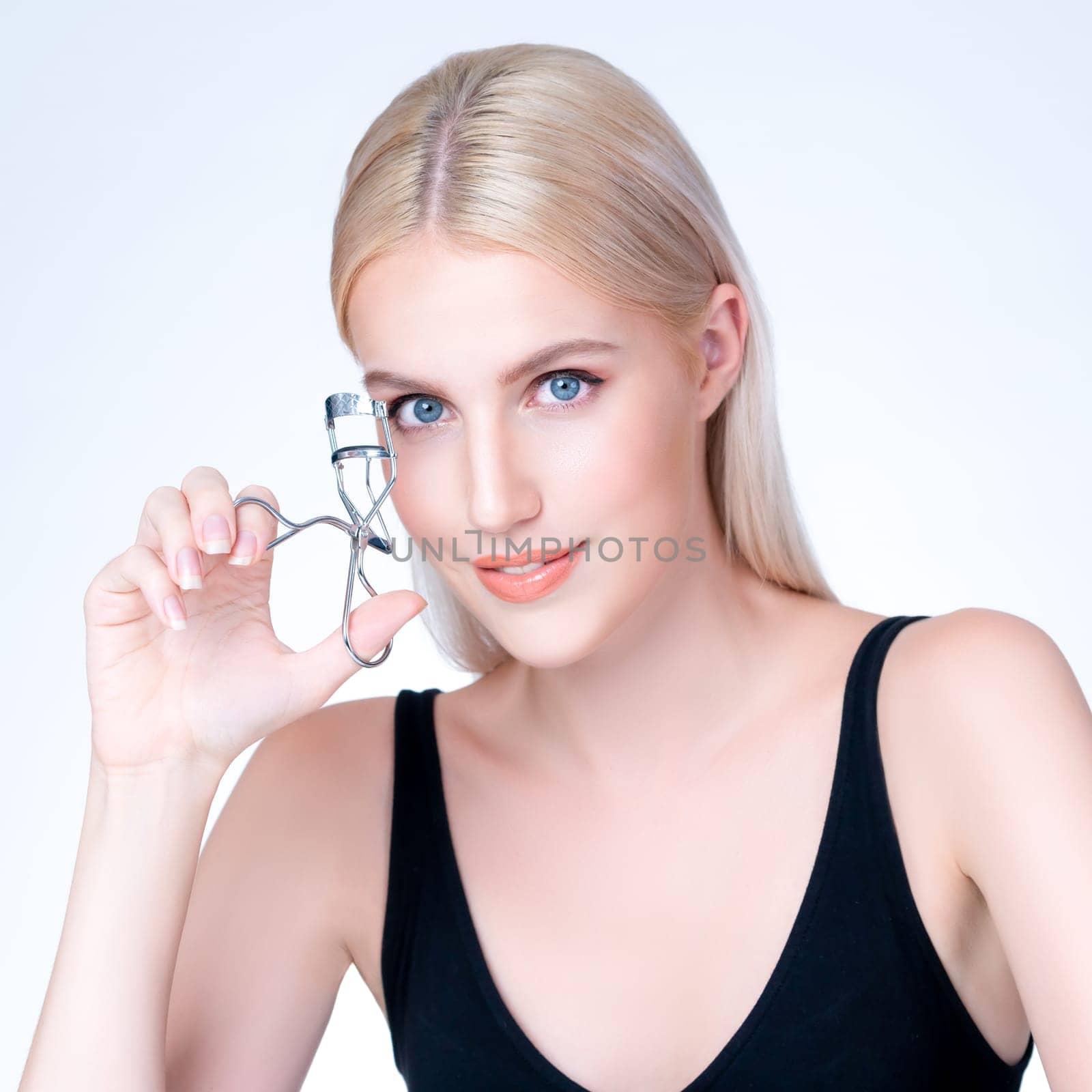 Personable woman correct eyelash curler with alluring facial makeup by biancoblue