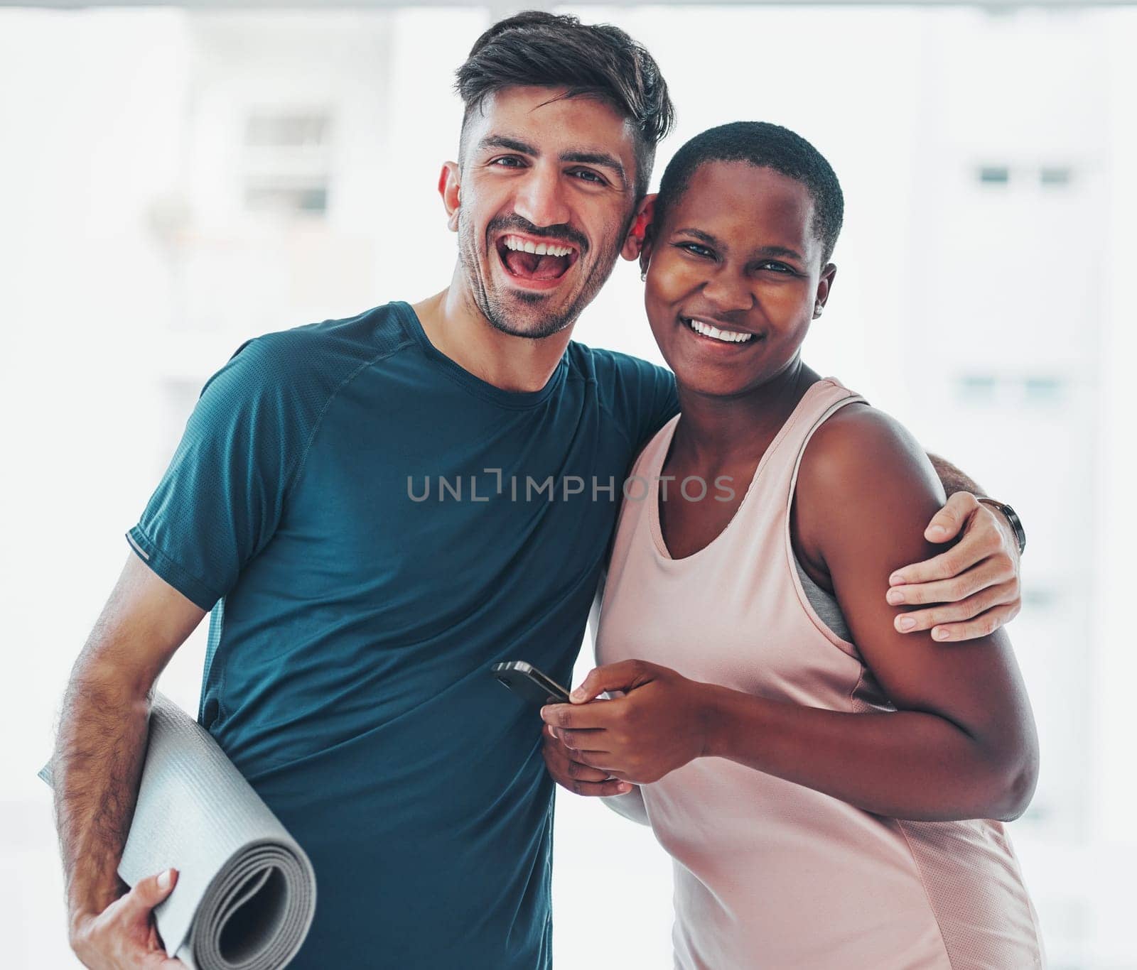 Portrait, yoga and a couple of friends in a studio for fitness while holding an exercise mat and phone together. Happy, excited and joy with diversity yogi people indoor for a wellness workout by YuriArcurs