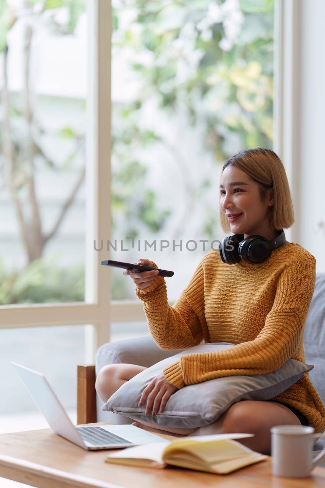 Young woman watching TV resting on sofa sitting in living room in house. Female watch film on television sitting on couch in apartment, leisure.