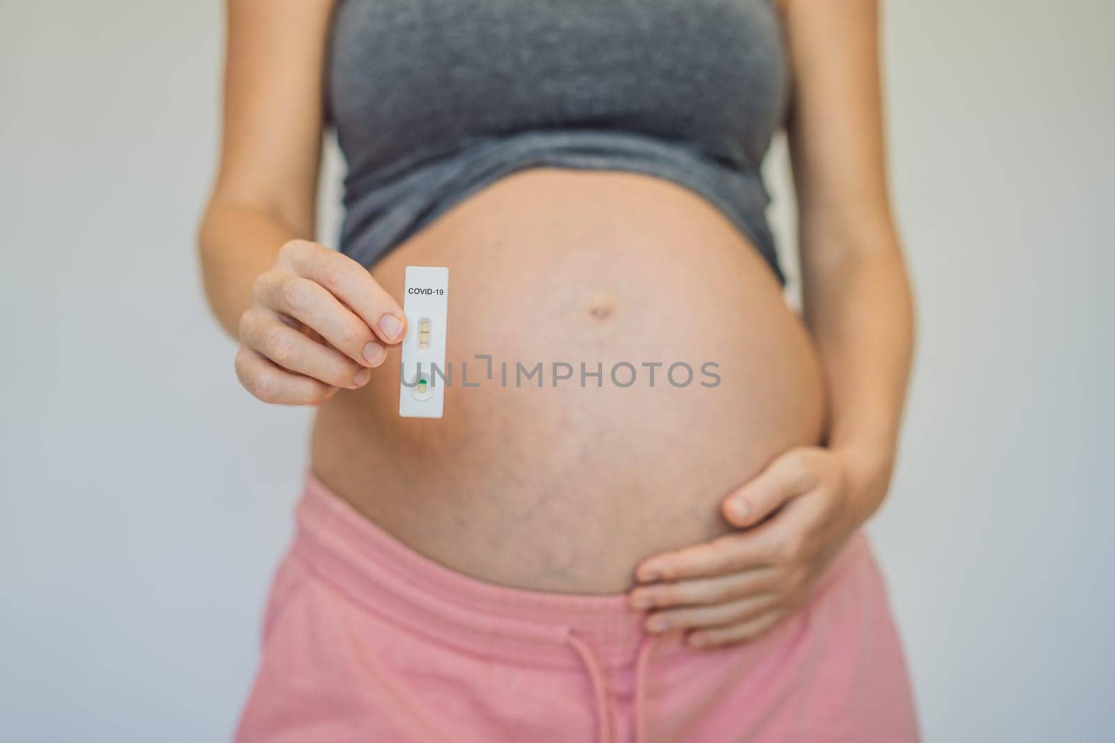 Pregnant woman making test. Close up of fingers holding express antigen covid corona test.