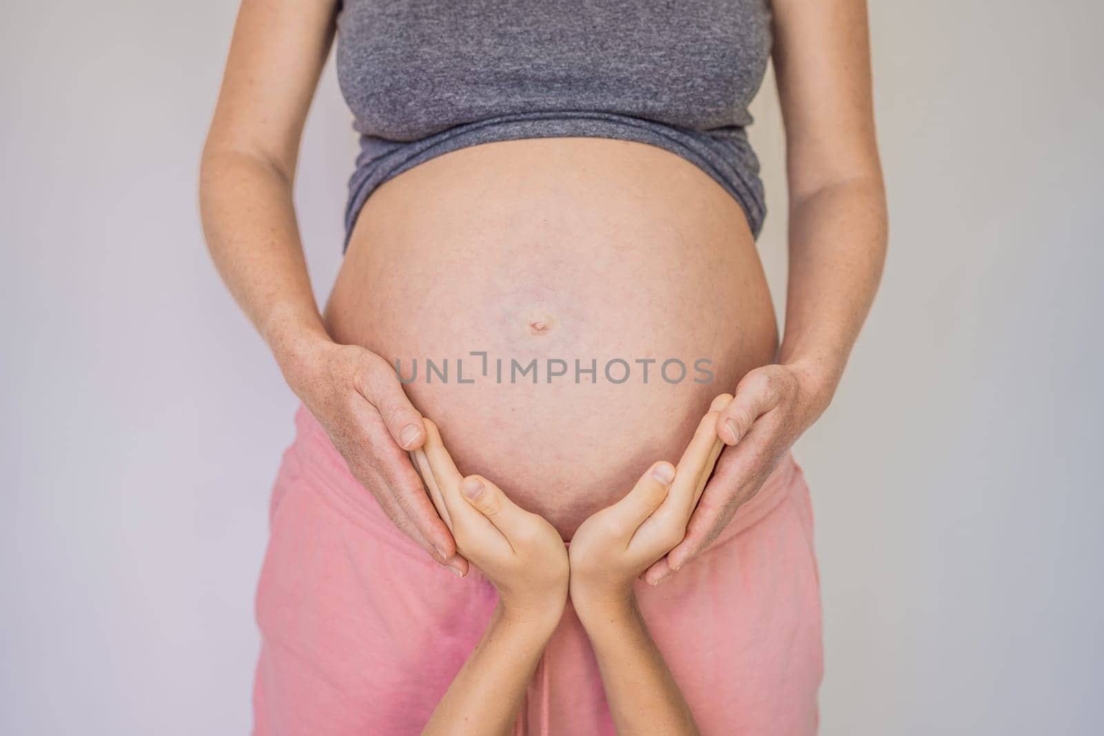 Young beautiful pregnant woman and eldest son. The cute boy put his hands on his mother's belly. Expecting a baby in the family concept. Preparing an older child for a younger one.