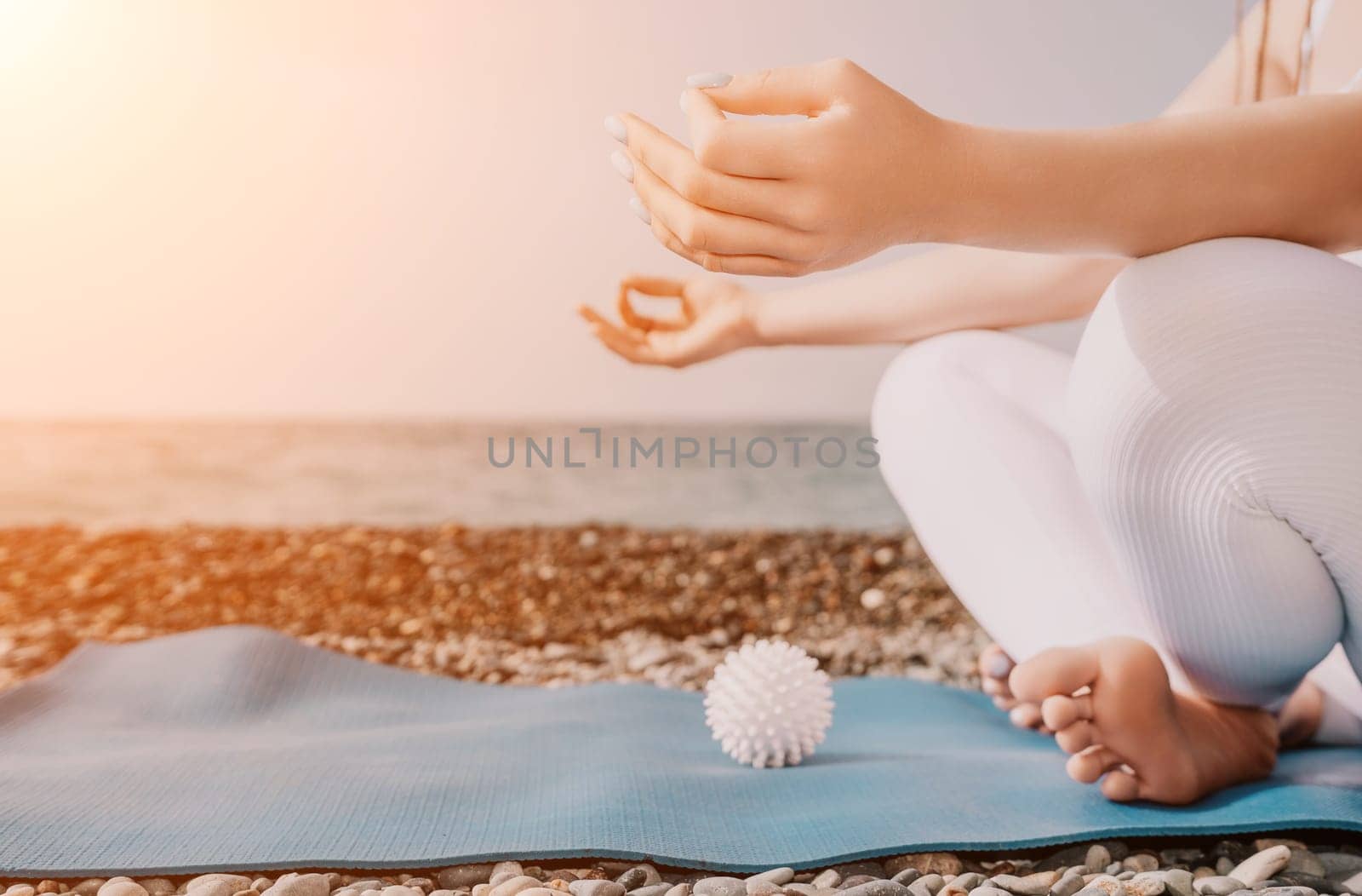 Woman yoga sea. Young woman with braids dreadlocks in white swimsuit and boho style braclets practicing outdoors on yoga mat by the ocean on sunny day. Women's yoga fitness routine. Healthy lifestyle, harmony