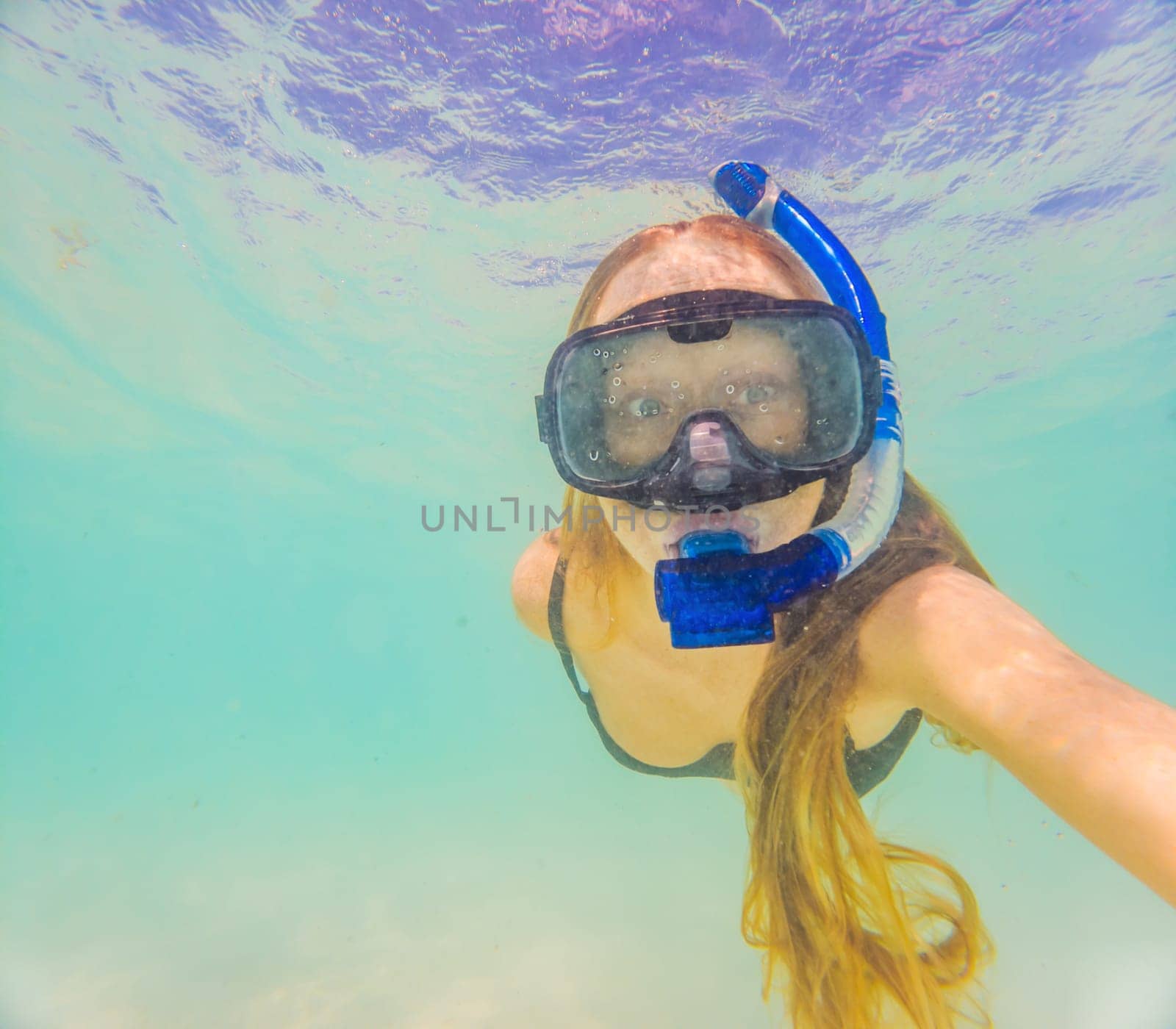 Woman with mask snorkeling in clear water by galitskaya