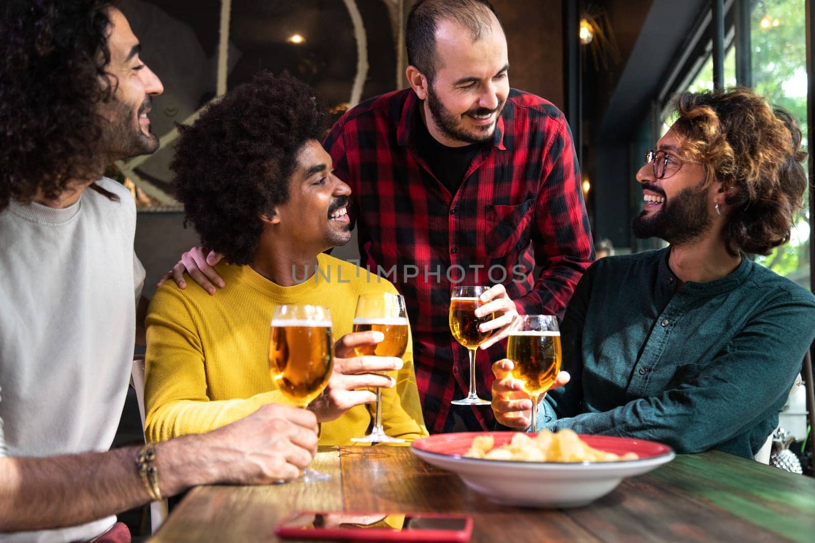 Group of happy male friends having beer in a pub. by Hoverstock