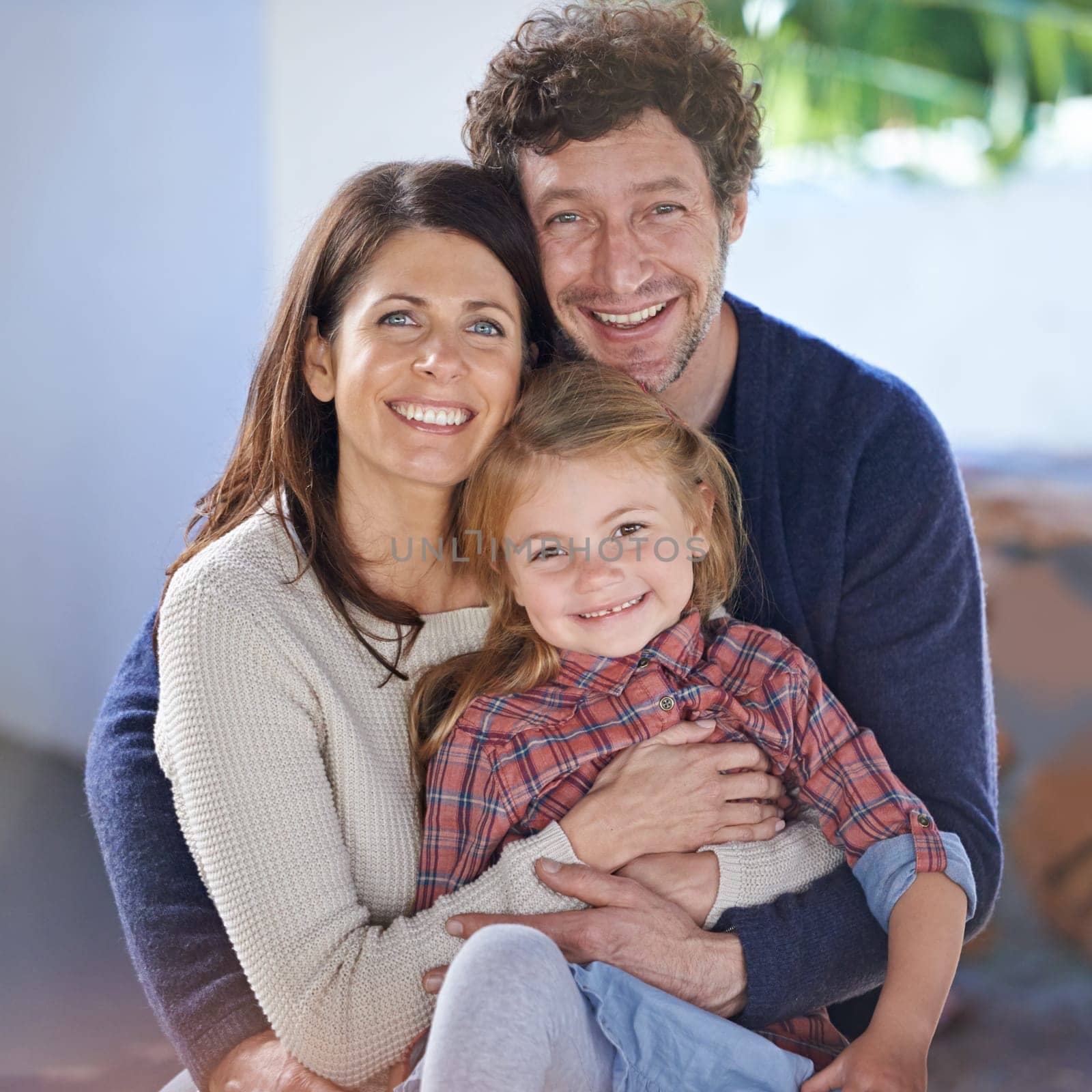Family hug in portrait, relax in backyard with mom and dad with kid with love and care outside house. Faces of happy people with smile, woman and man with girl child together at home outdoor.