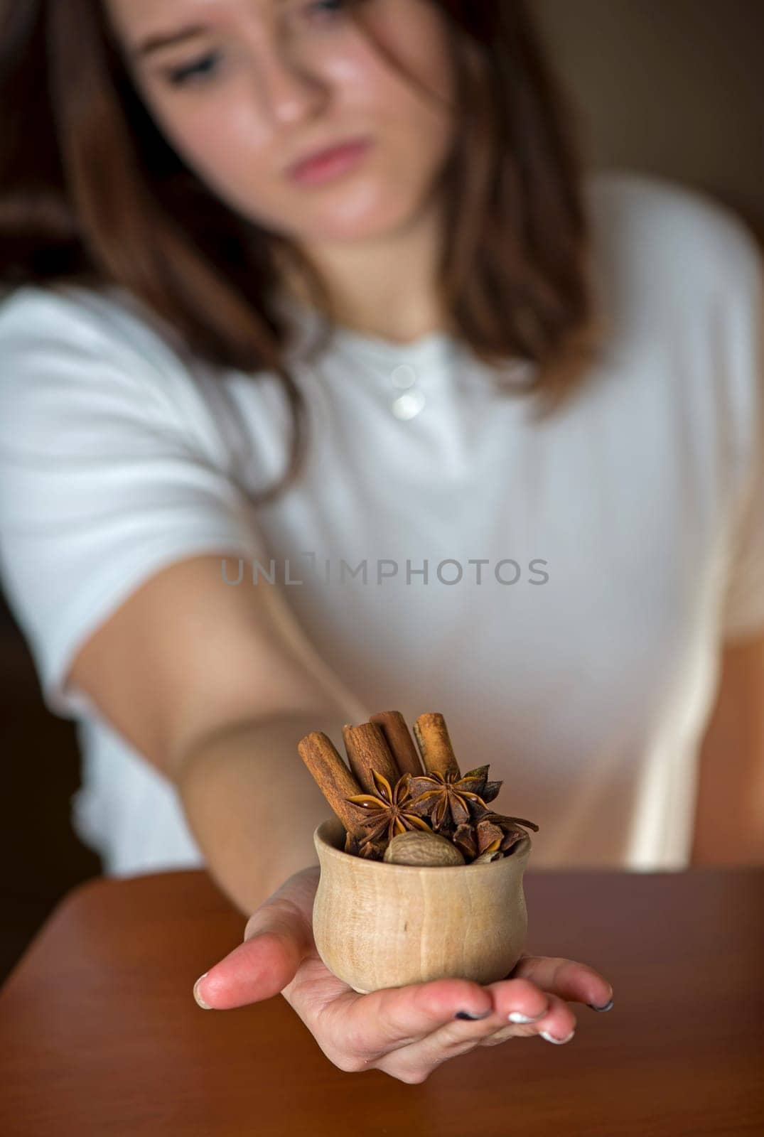 A girl shows a cup with spices for mulled wine in a kitchen decorated for Christmas by aprilphoto