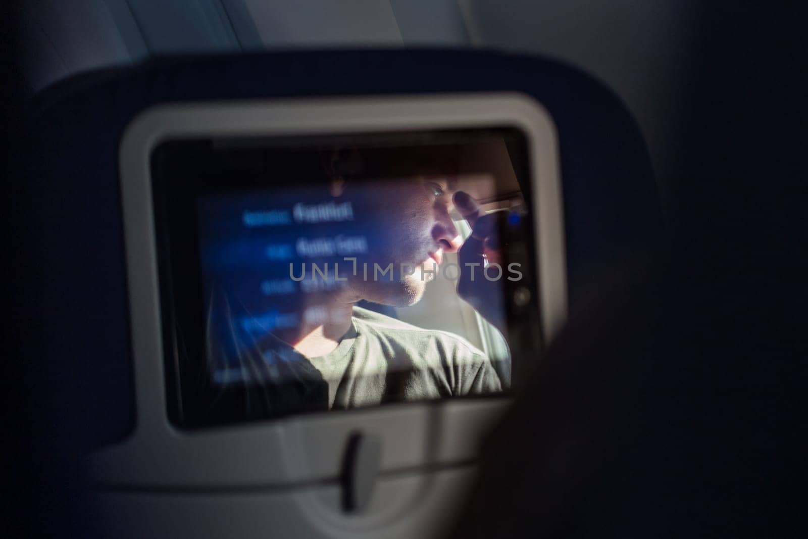 Reflection of a passenger on an airplane touch screen monitor during long flight. Entertainment service system in aircraft. by kasto