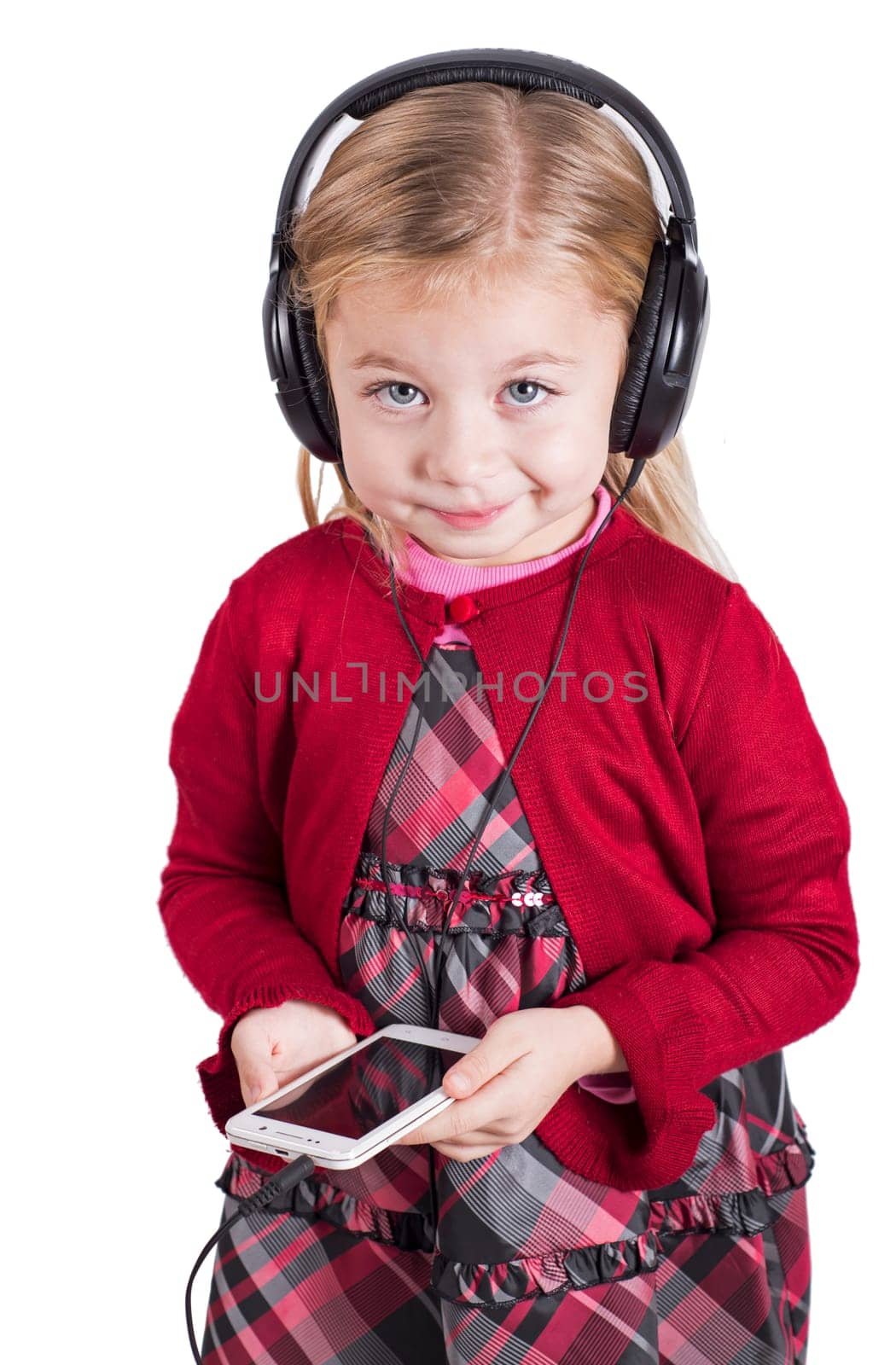 Education concept. An inquisitive child. Little blonde girl smiling while listening to music on smartphone mobile device with headphones by aprilphoto