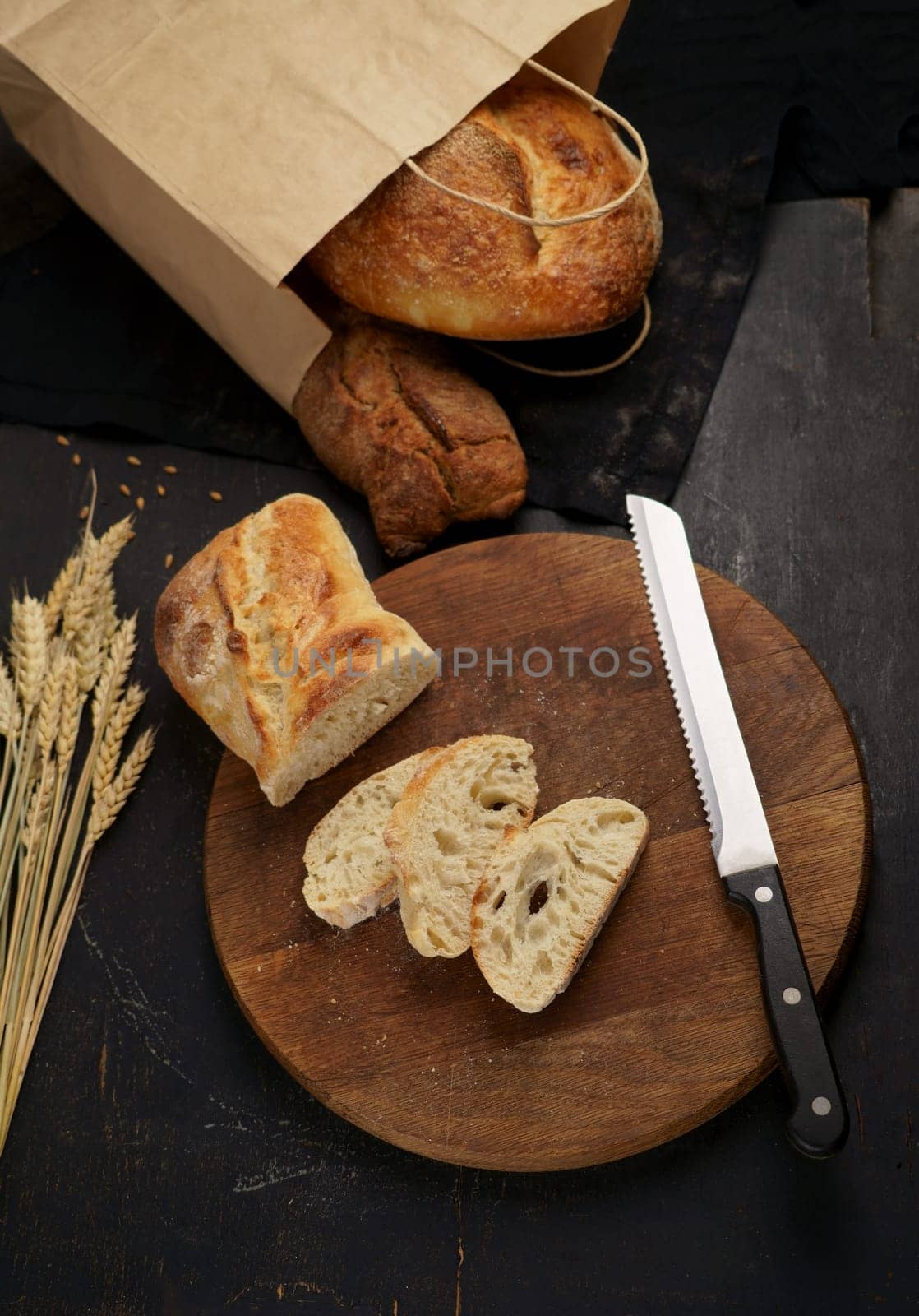 Whole grain bread put on kitchen wood plate with a knife for cut. Fresh bread on table close-up. Fresh bread on the kitchen table Freshly baked rye bread on a wooden board. by aprilphoto