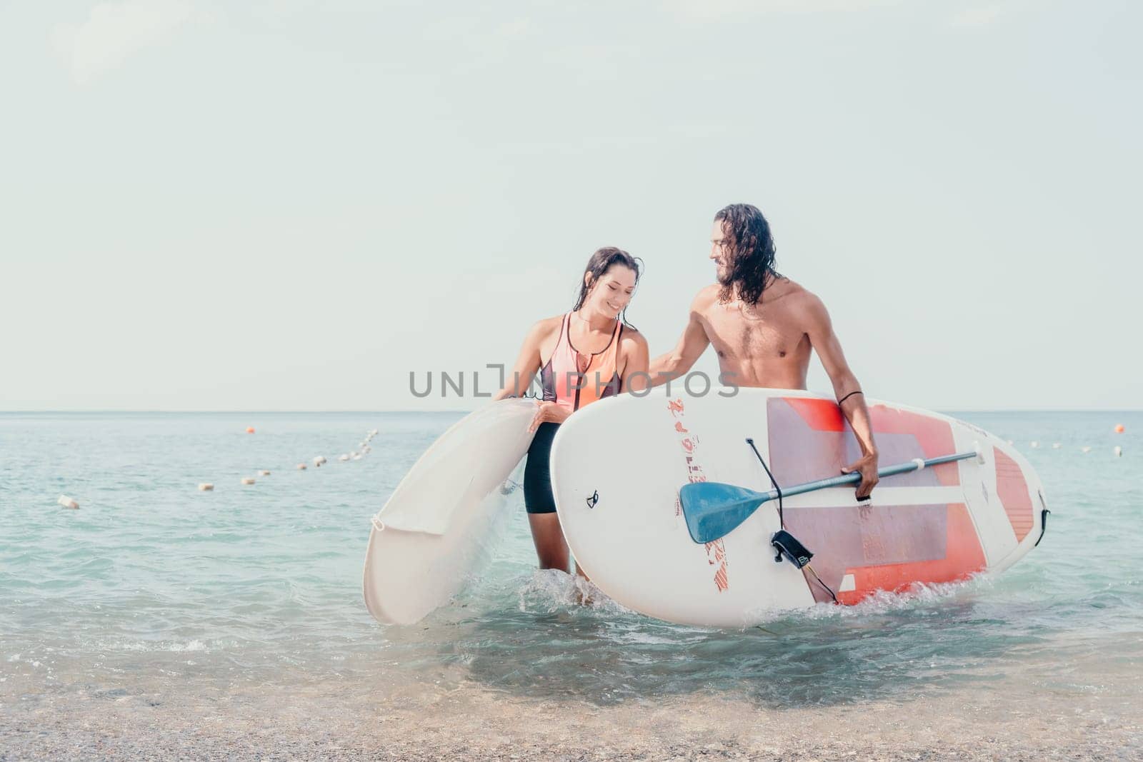 Woman man sea sup. Close up portrait of beautiful young caucasian woman with black hair and freckles looking at camera and smiling. Cute woman portrait in a pink bikini posing on sup board in the sea by panophotograph