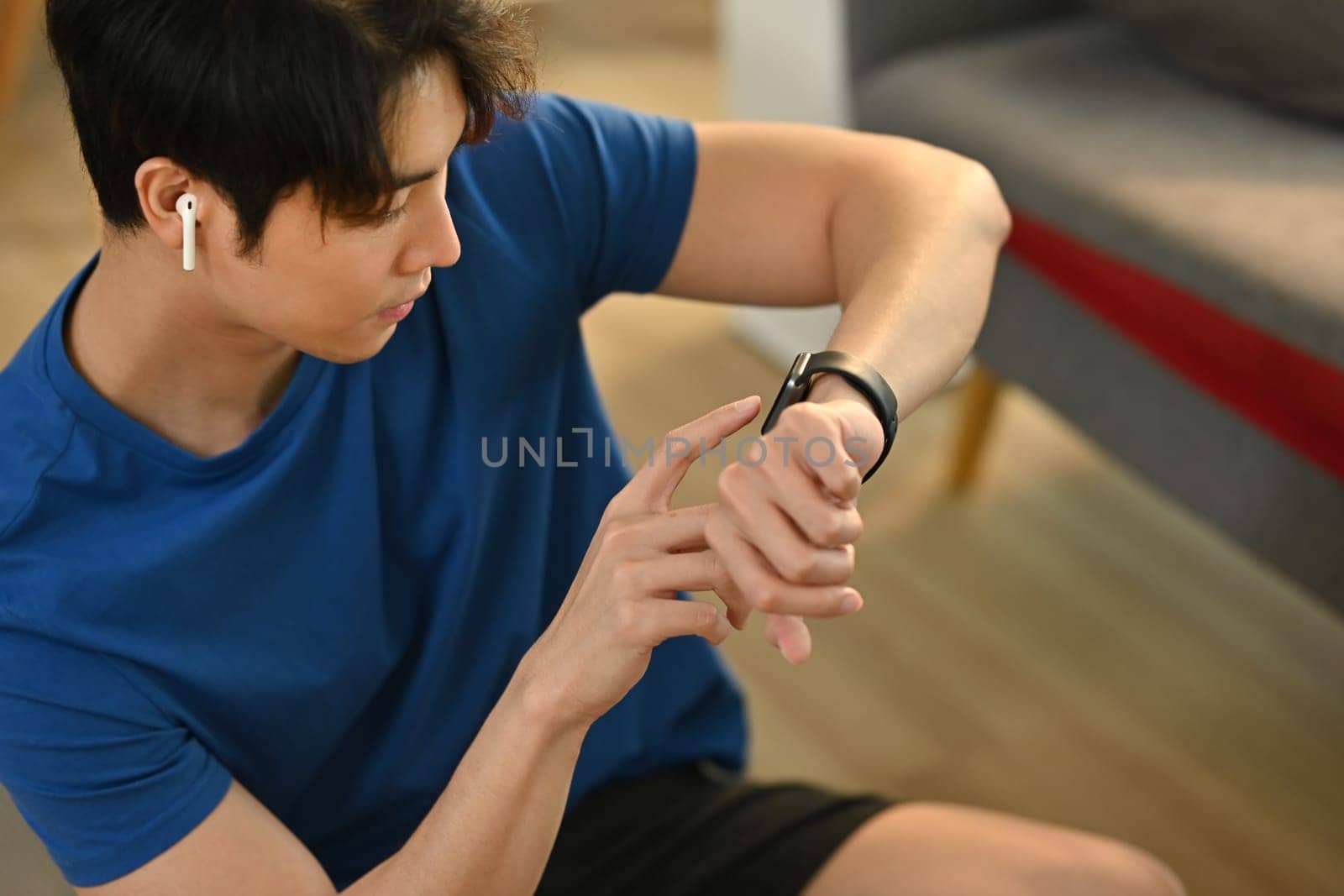 Young fitness man checking smartwatch to monitor training results. Technology health, wellness concept by prathanchorruangsak