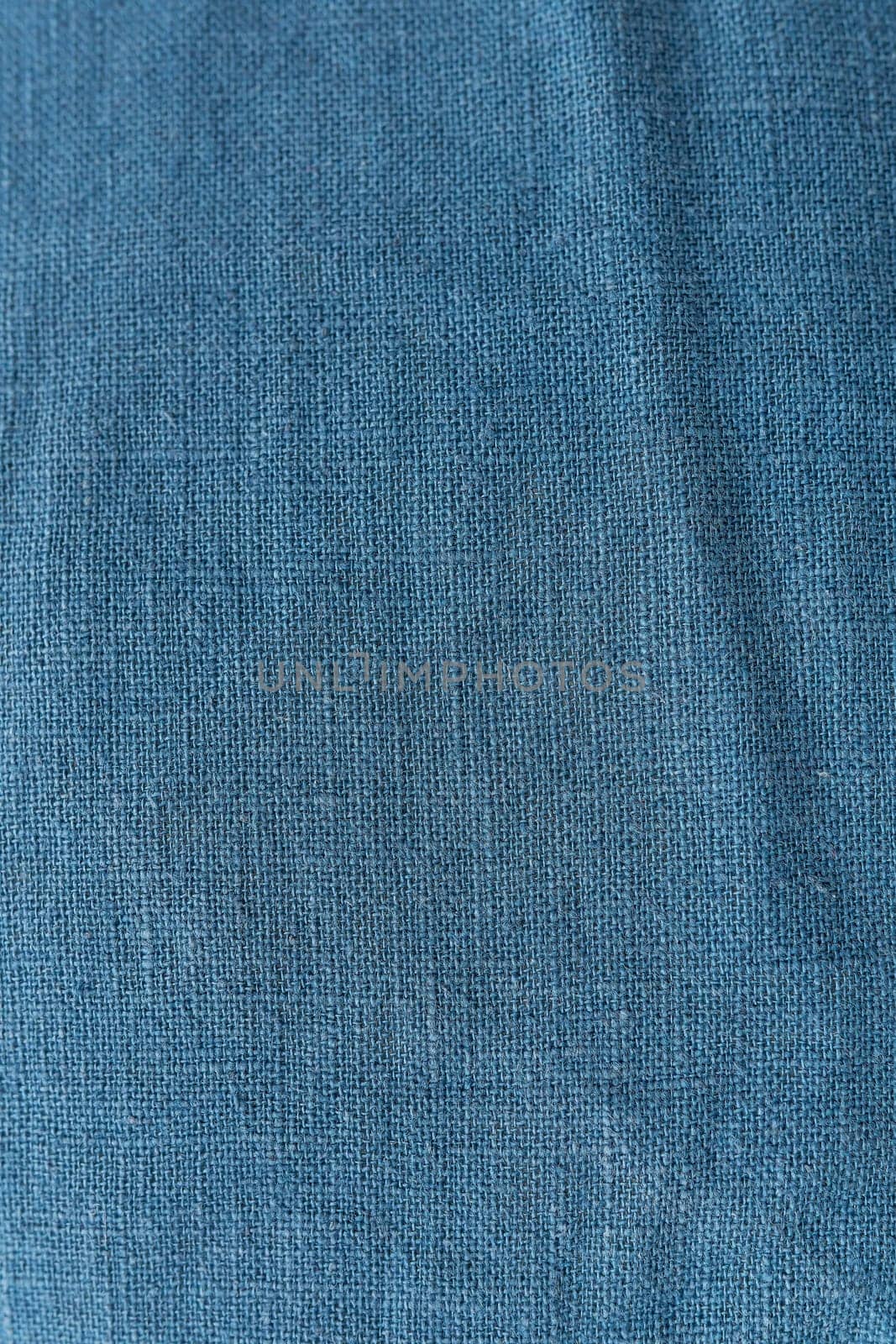 Classic blue color, vertical photo. Linen fabric blue background texture. Crumpled linen dark blue fabric