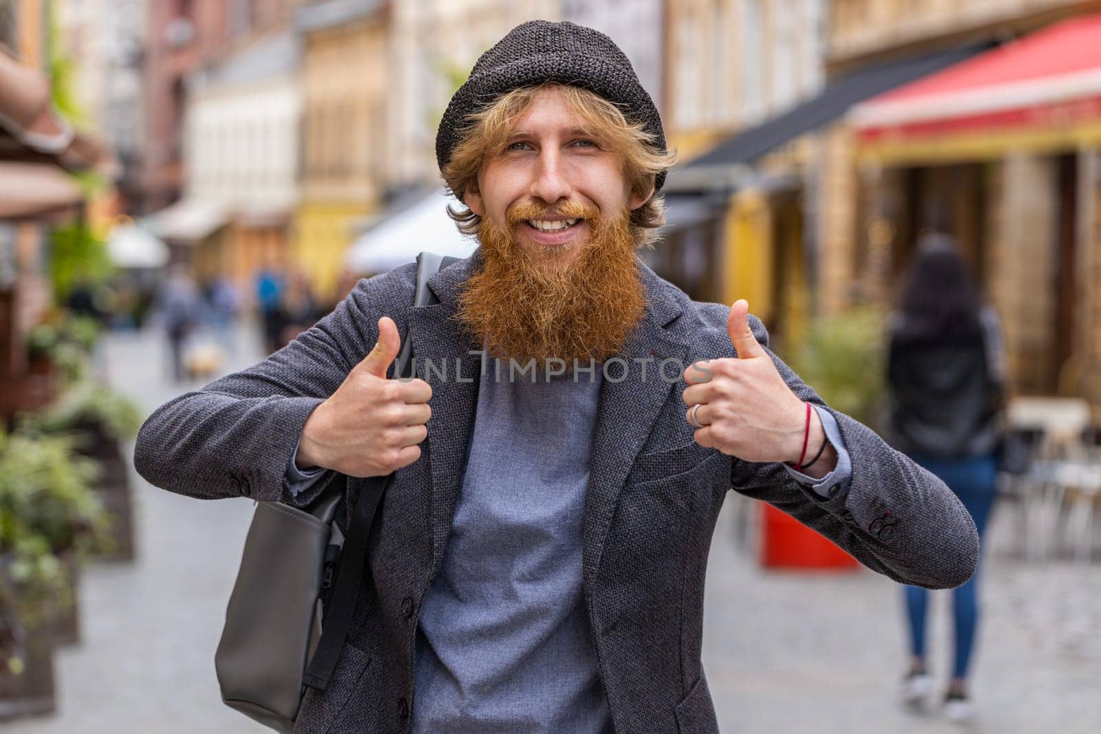 Like. Happy young bearded man looking approvingly at camera showing thumbs up, like sign positive something good positive feedback. Redhead guy walking in urban city street. Town lifestyles outdoor