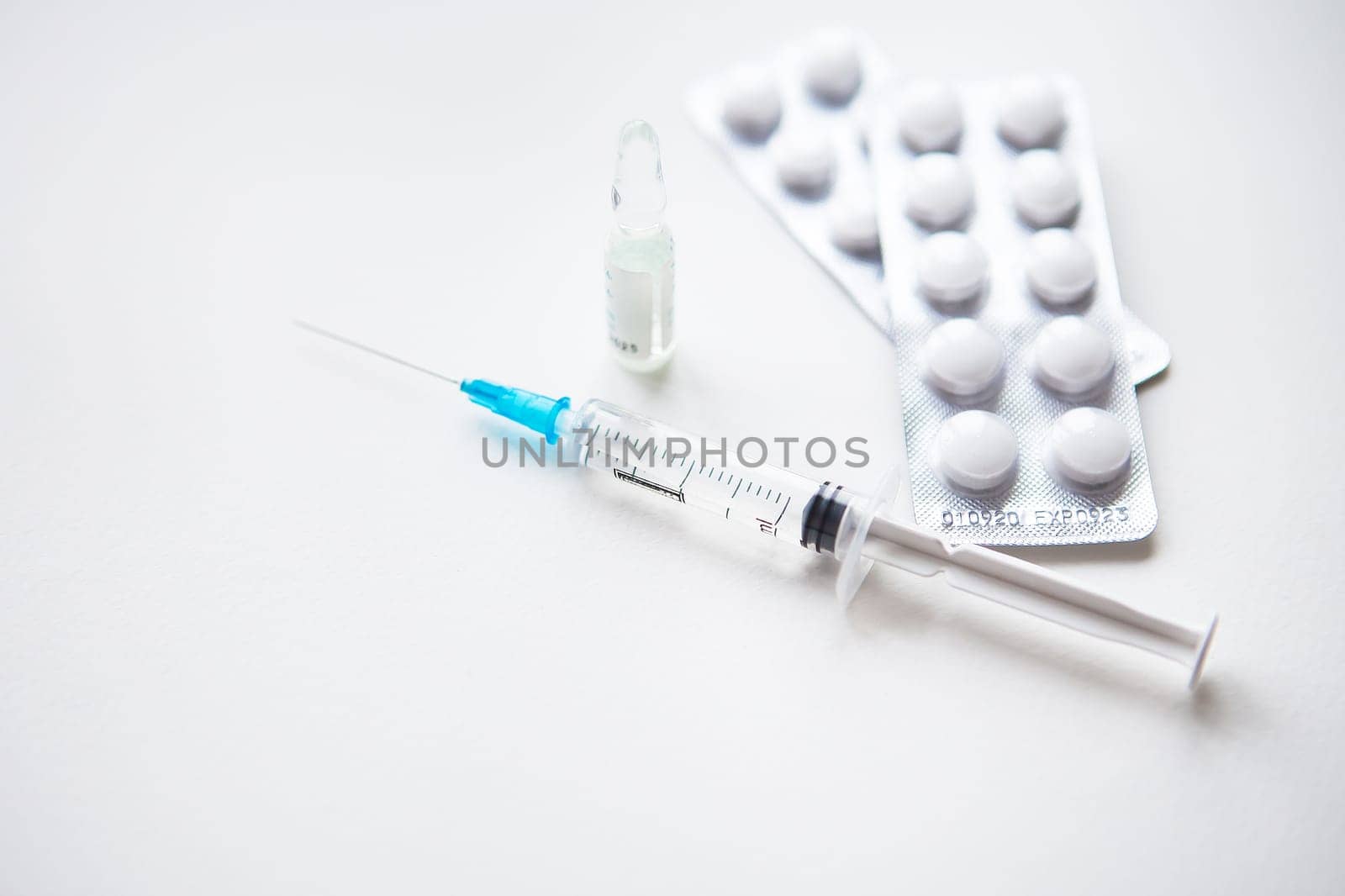 Preparation for vaccination against covid-19. Syringe, vaccine, pills, medical mask on a white table