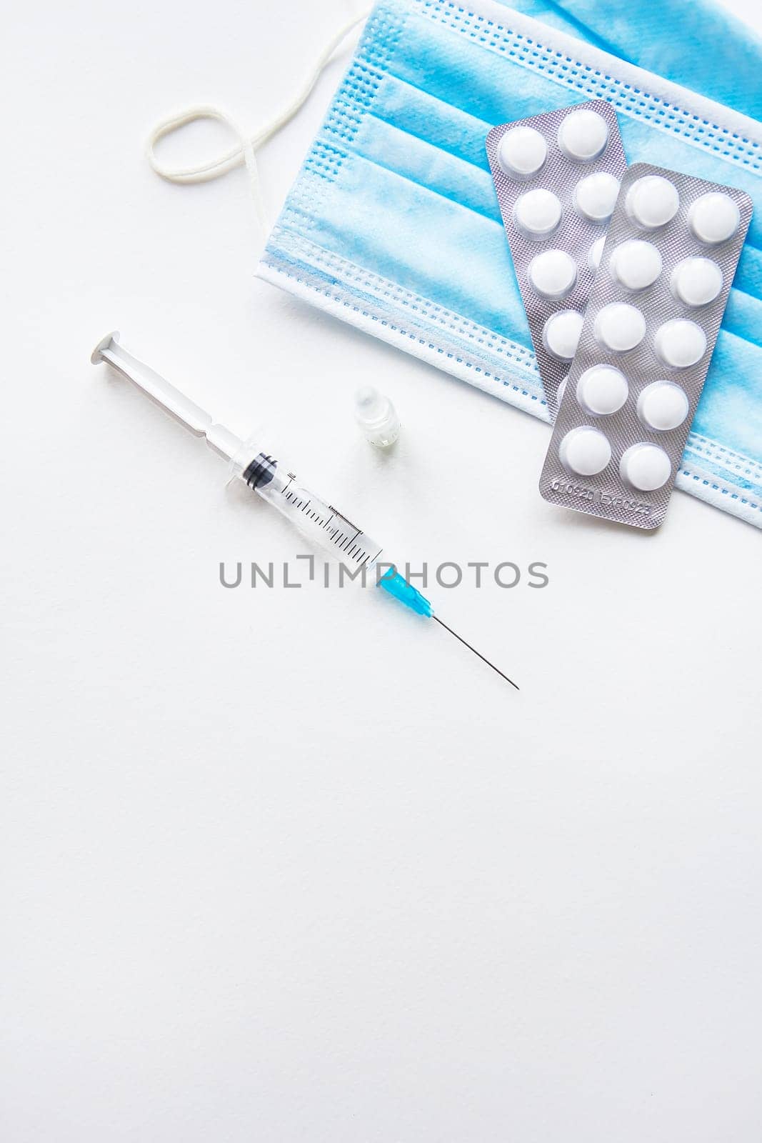 Preparation for vaccination against covid-19. Thermometer, pills, medical mask on a white table. Place for an inscription, vertical photo. by sfinks