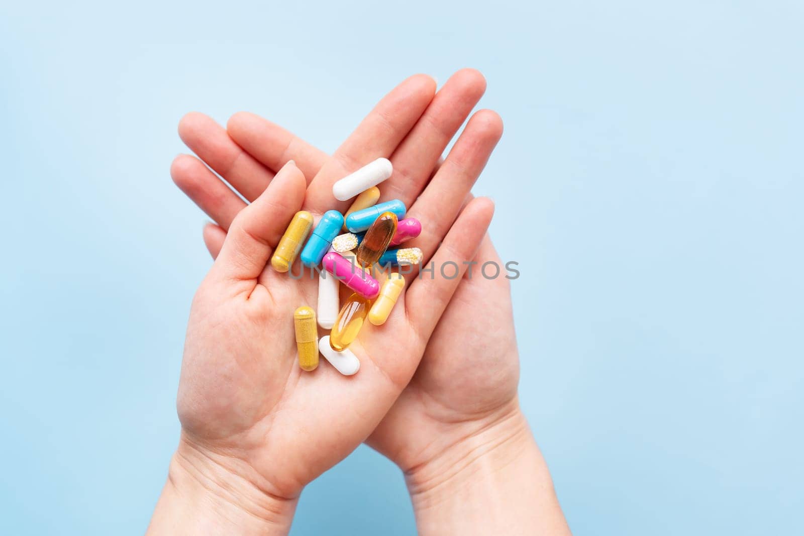 The girl holds a handful of brightly colored vitamins, nutritional supplements, and medicines in her palms. Concept of medicine and health support