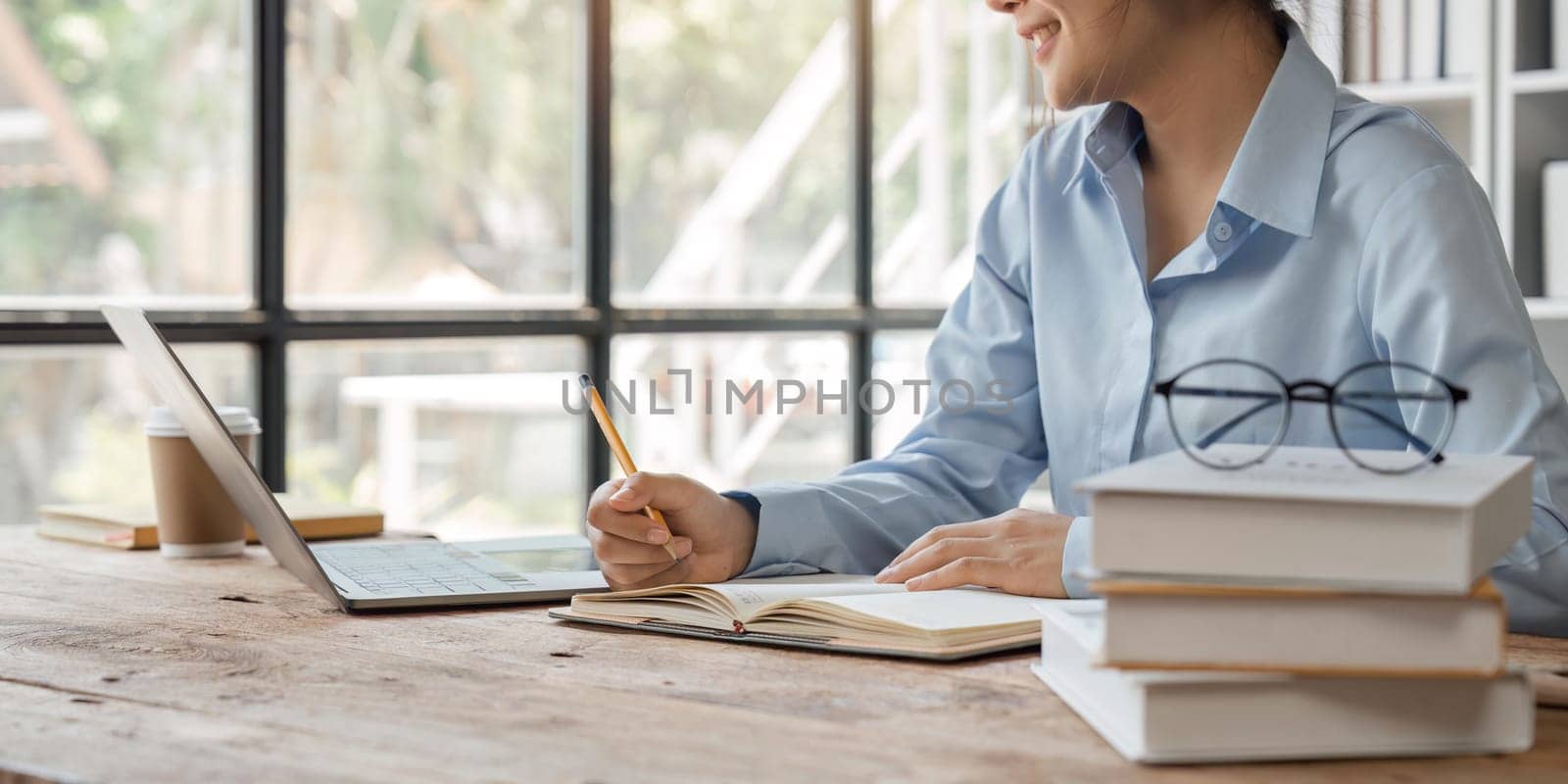 Young woman student busy study make notes in notebook and using laptop concentrated online training course technology education.