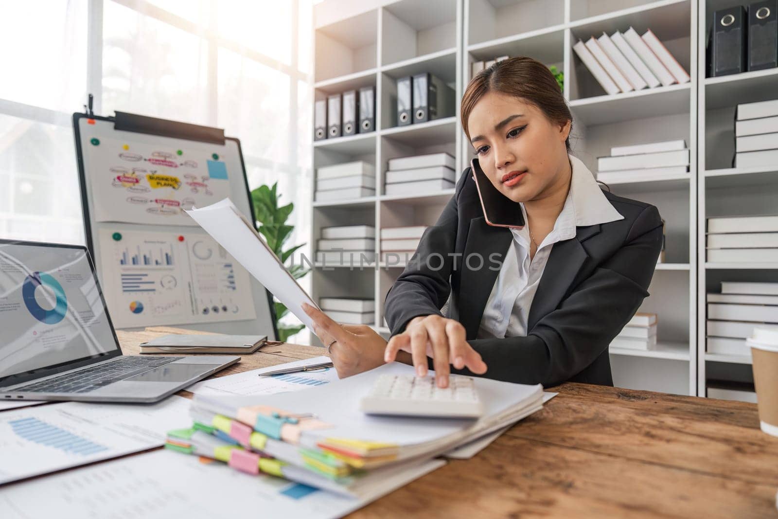 business woman sitting at office desk in front of laptop hold mobile phone make pleasant business or informal call. Successful businessman at calculate financial on calculator.