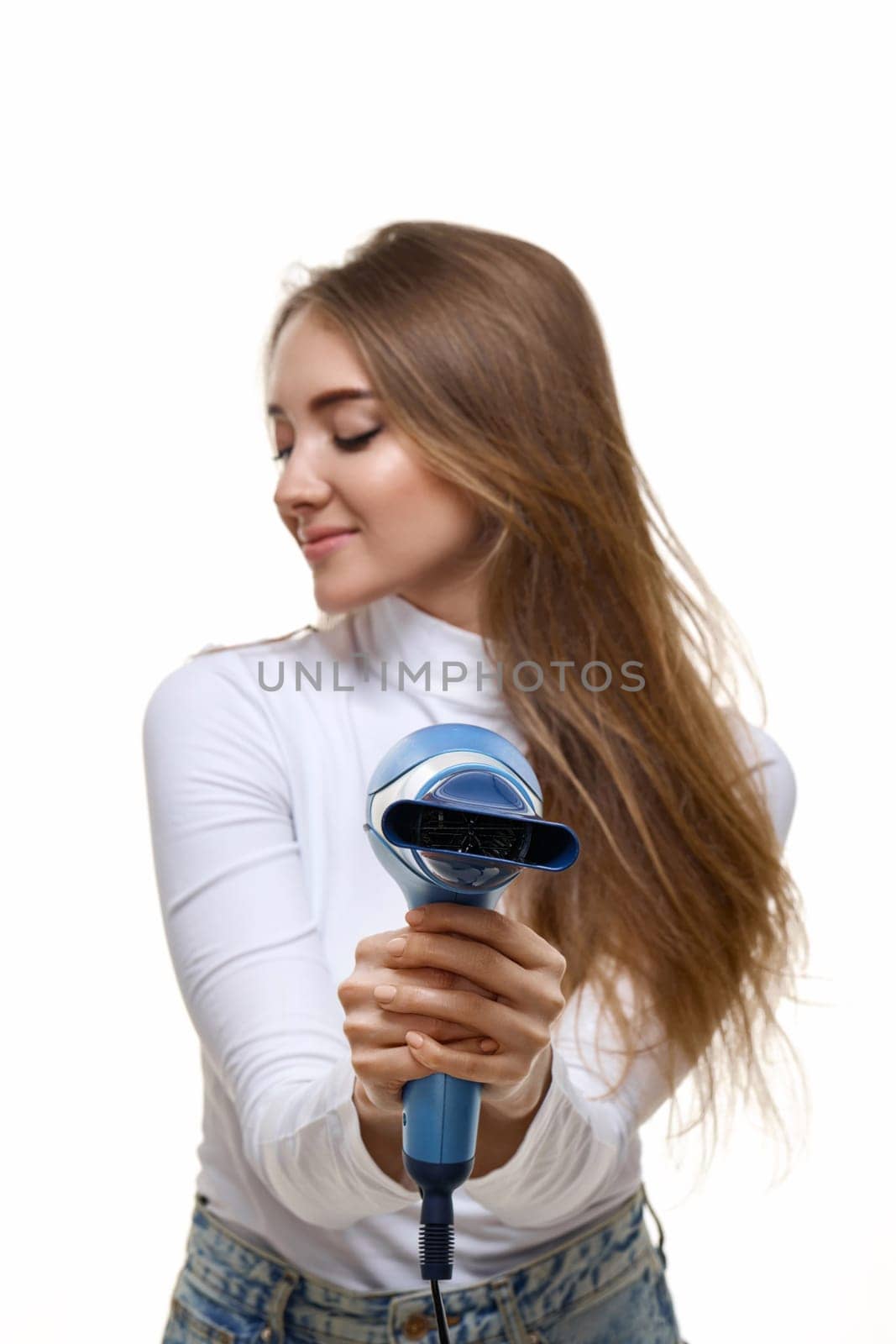 Portrait of attractive cheerful girl drying long hair. focus on hair dryer
