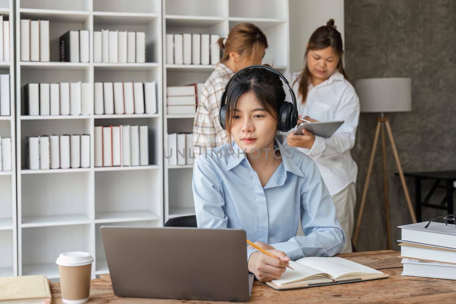 Smiling girl with headset studying online, using laptop.