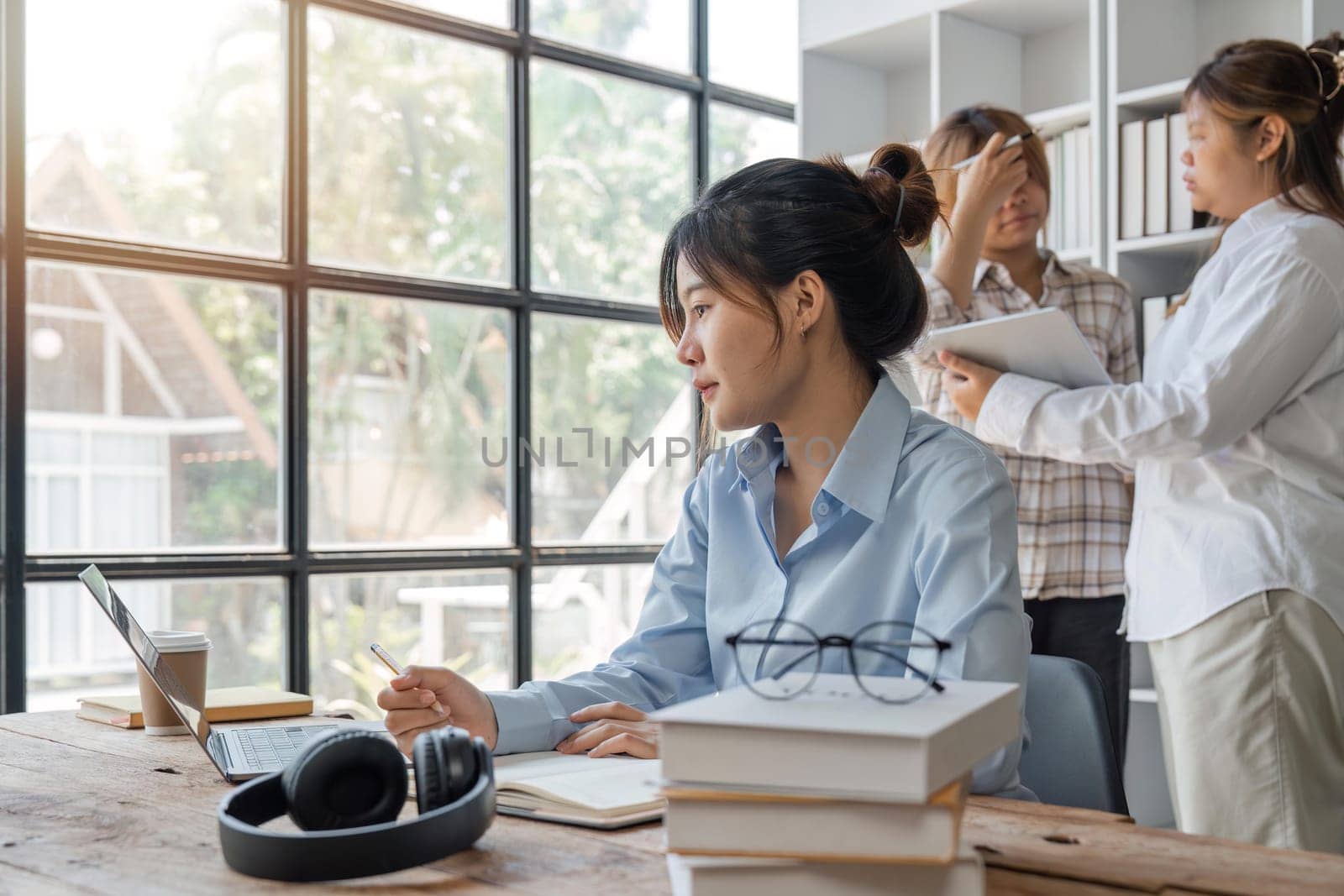 cute stylish female student, studying remotely from home, using a laptop, taking notes on notepad during online lesson, e-learning concept, smiling.