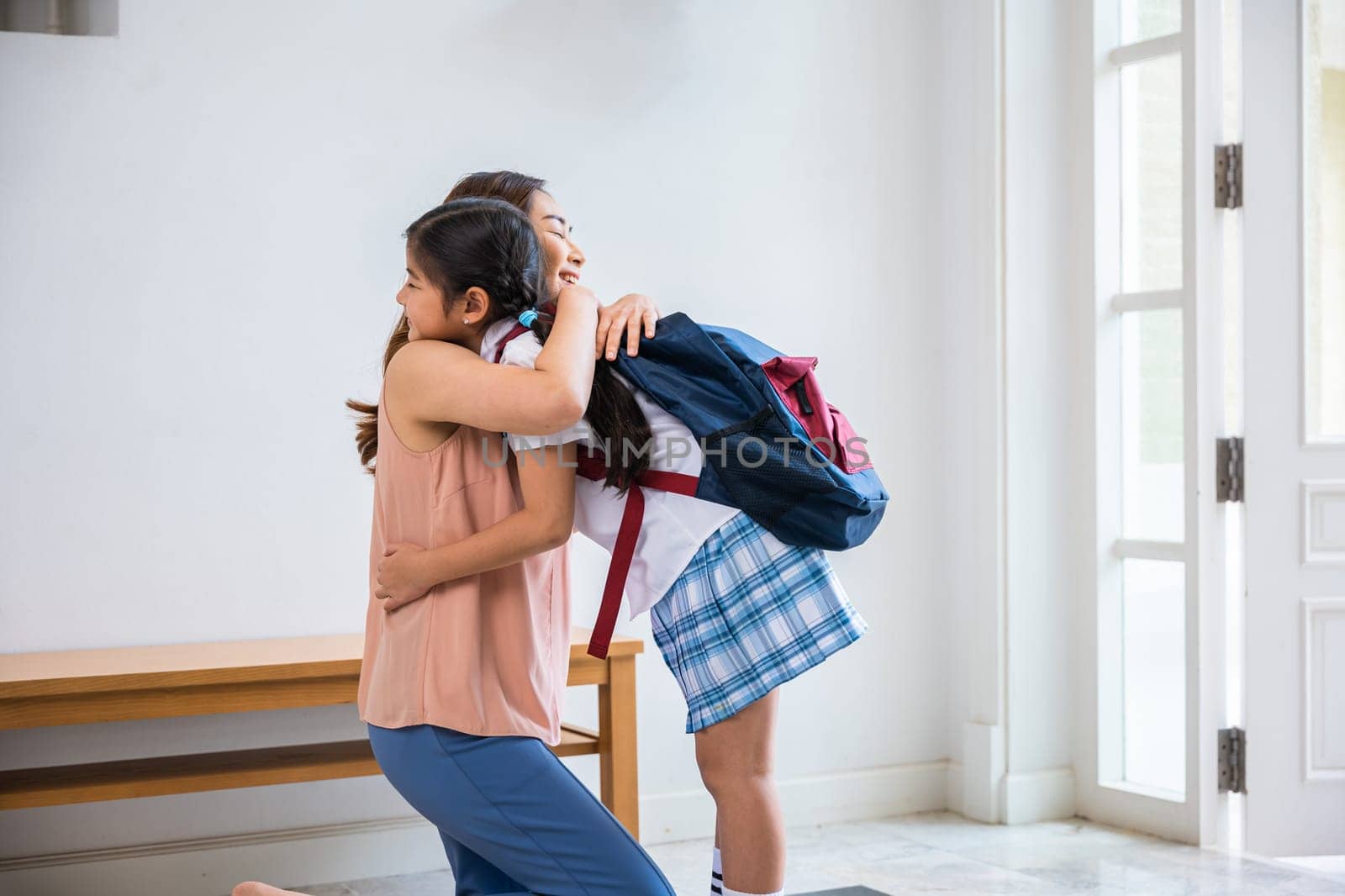 Loving mother and schoolgirl with backpack before first day, Asian mother hugging her daughter saying goodbye before go to school at home, parents and child little girl, back to school concept