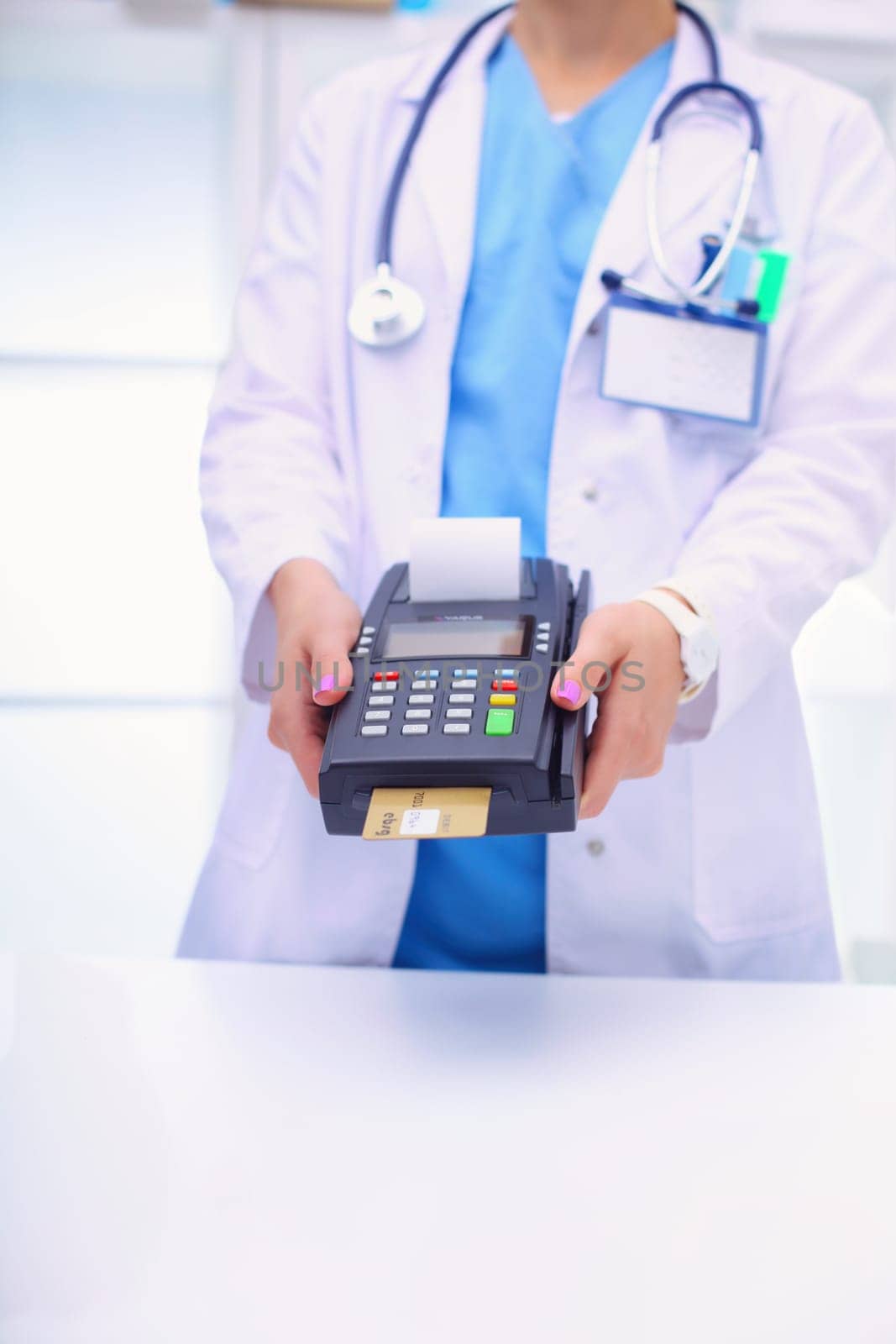 Doctor is holding payment terminal in hands. Paying for health care. Doctor.