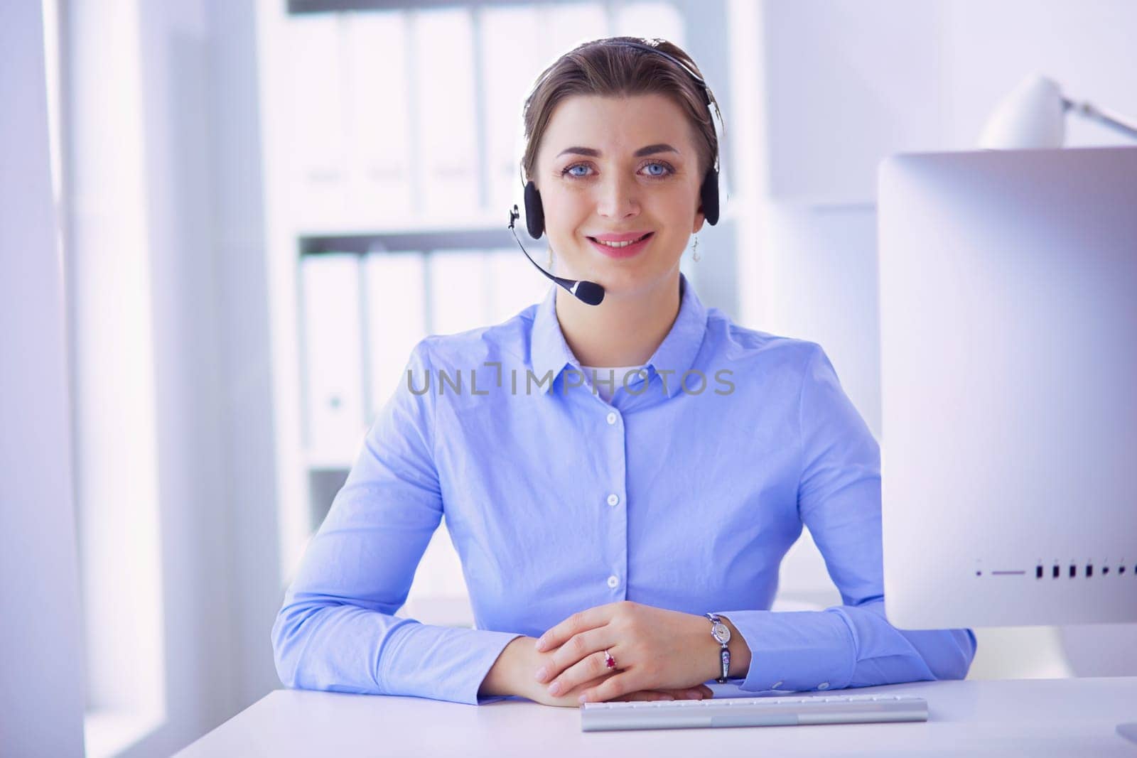 Serious pretty young woman working as support phone operator with headset in office.
