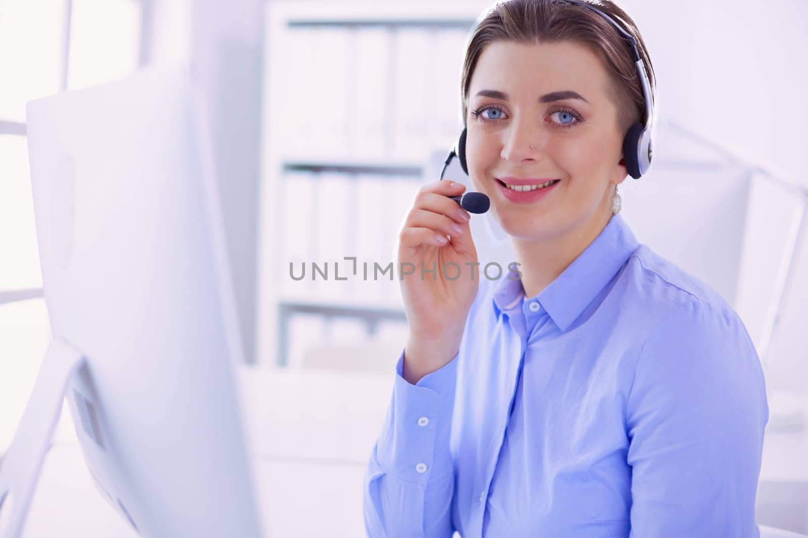 Serious pretty young woman working as support phone operator with headset in office.