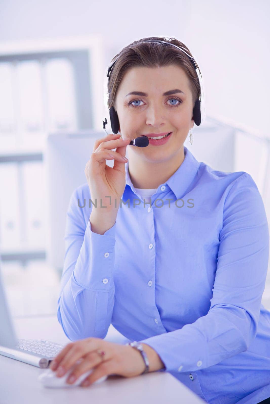 Serious pretty young woman working as support phone operator with headset in office.