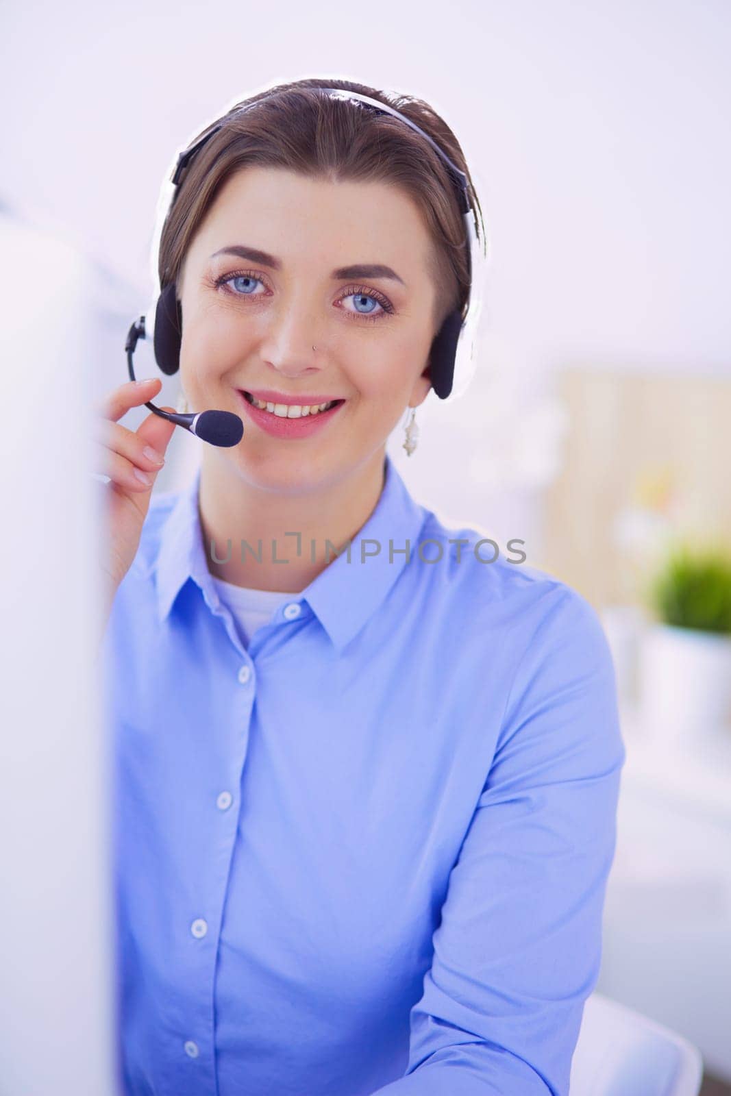 Serious pretty young woman working as support phone operator with headset in office.