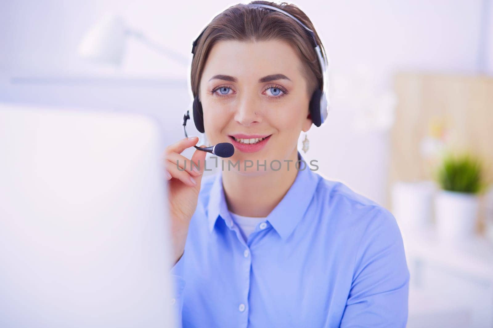 Serious pretty young woman working as support phone operator with headset in office.