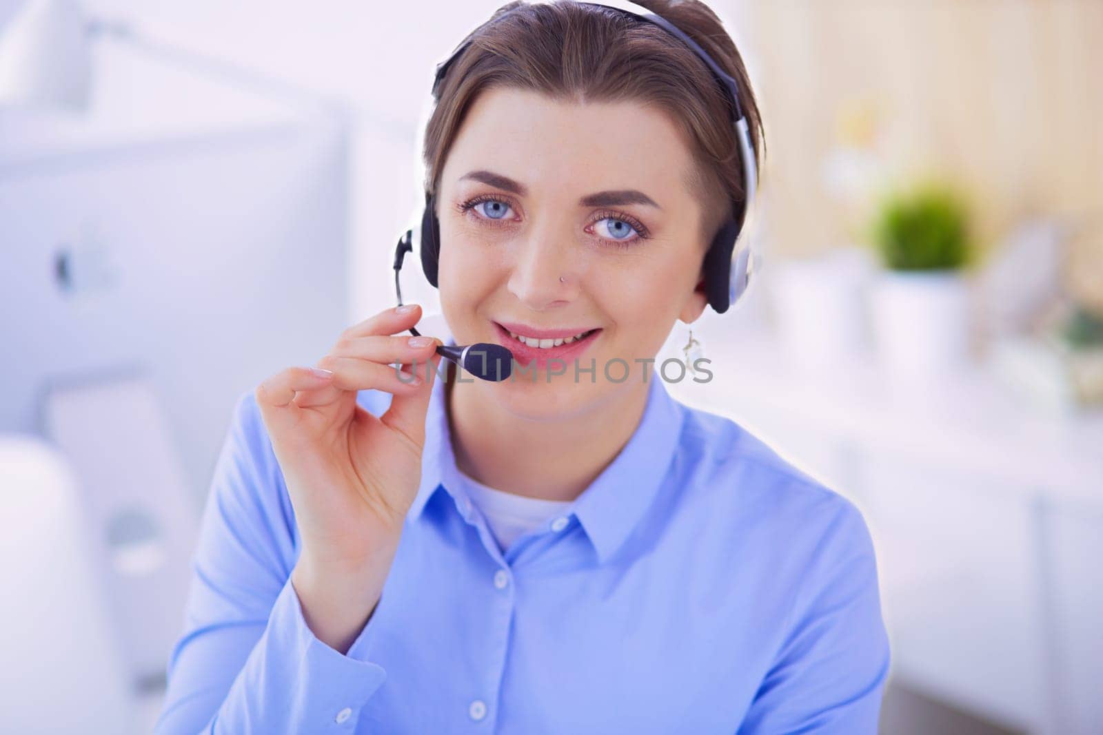 Serious pretty young woman working as support phone operator with headset in office.